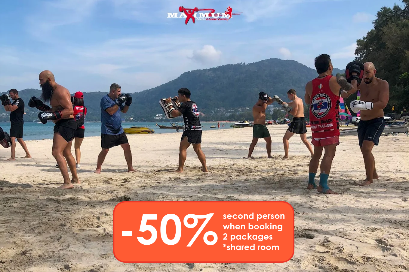 Group of men practicing Muay Thai on a sandy beach with a mountainous landscape in the background. Some are wearing boxing gloves, shorts, and sports gear. An advertisement overlay offers a 50% discount for booking two packages with shared rooms.