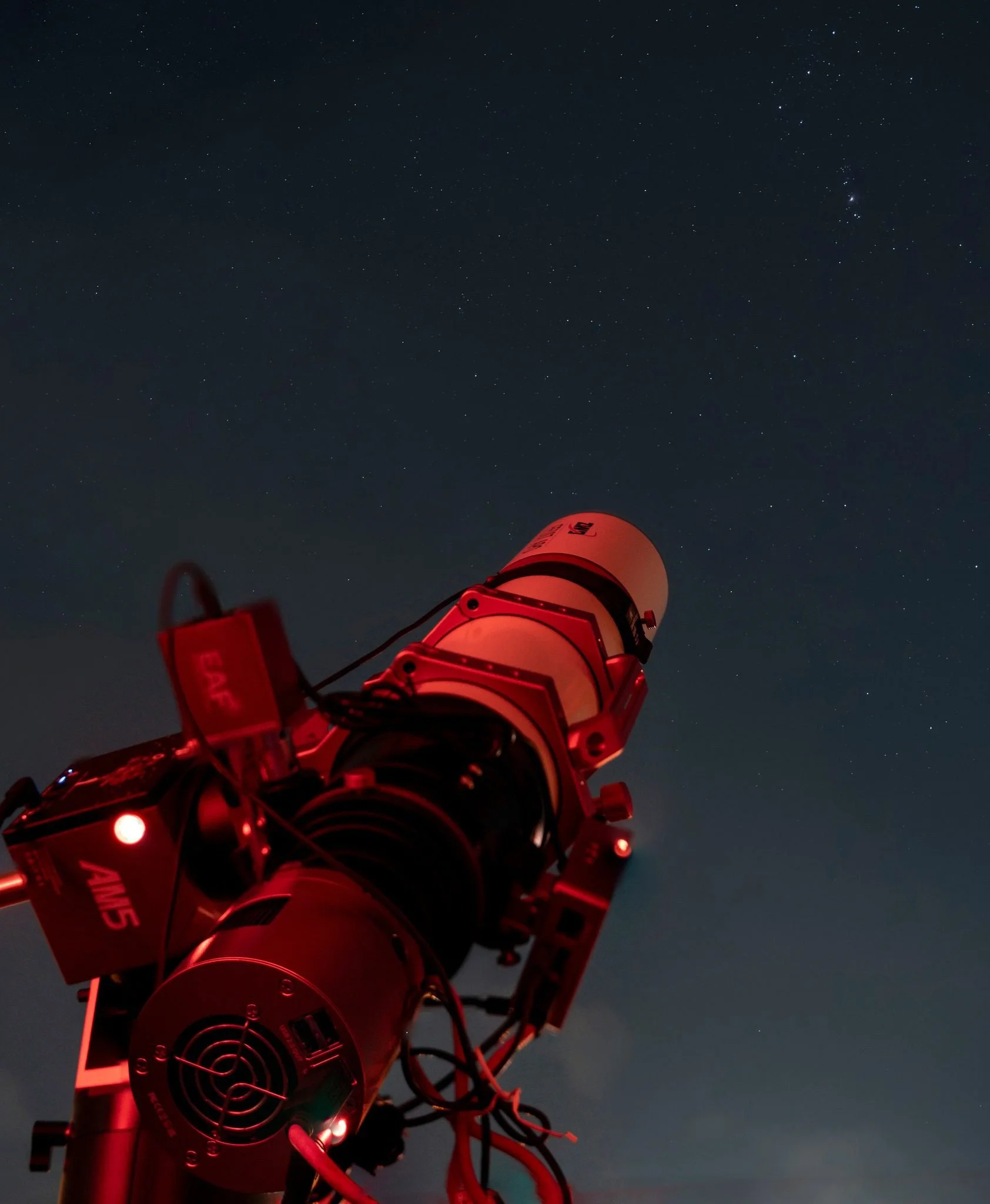 A telescope pointed towards a starry night sky.