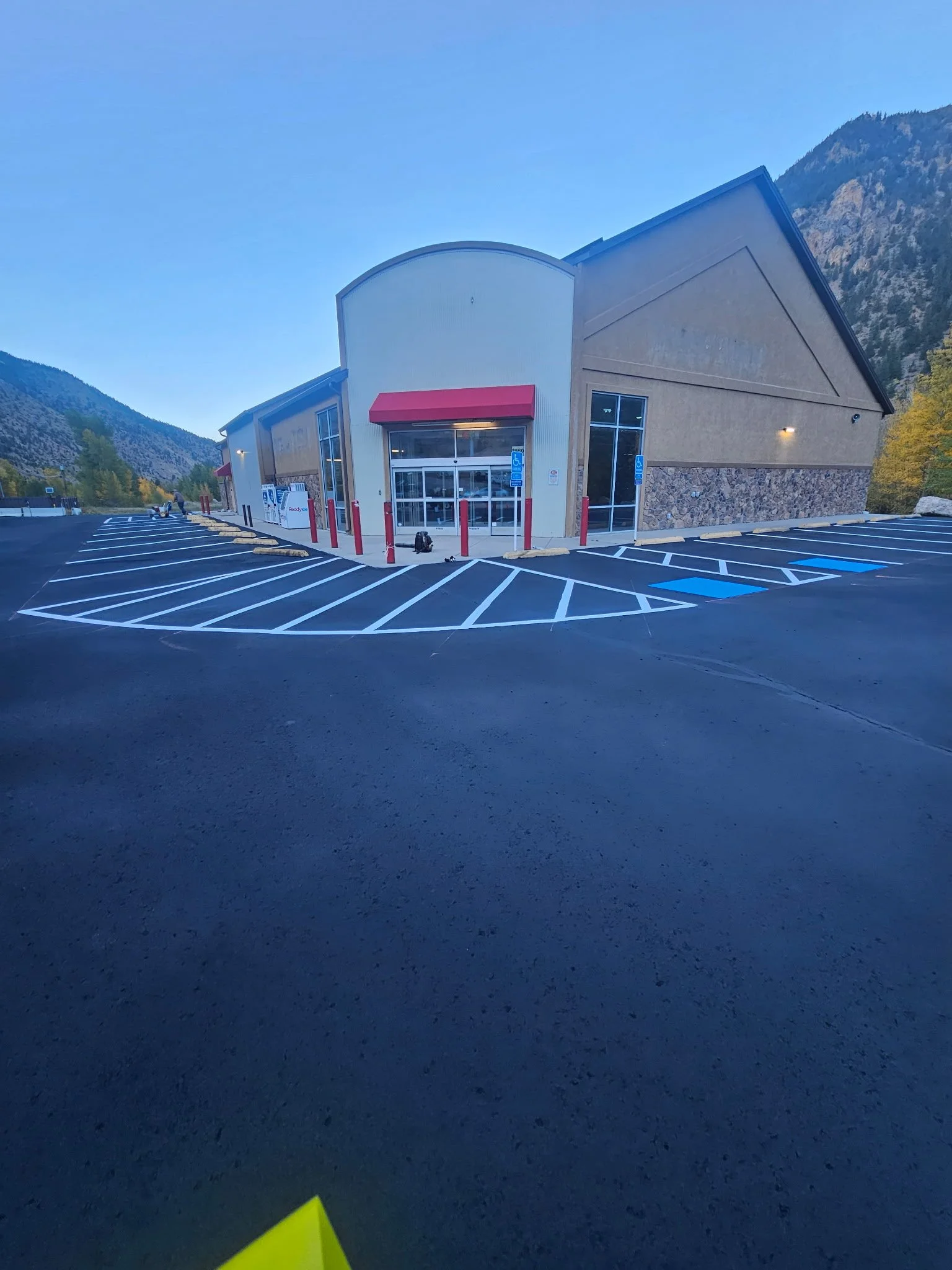 Empty parking lot in front of a retail store with mountain scenery in the background.