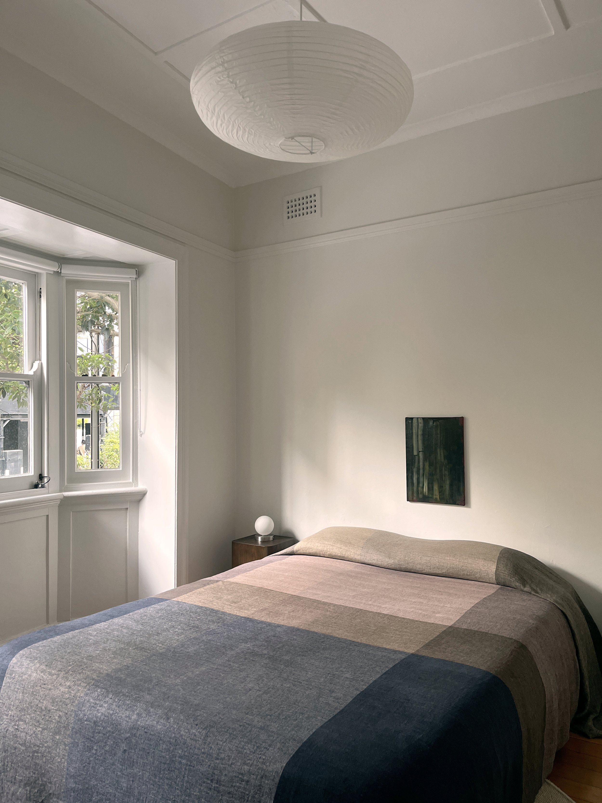 A softly lit bedroom corner highlighting natural light, warm tones, and restrained styling. A calm, contemporary interior composition.