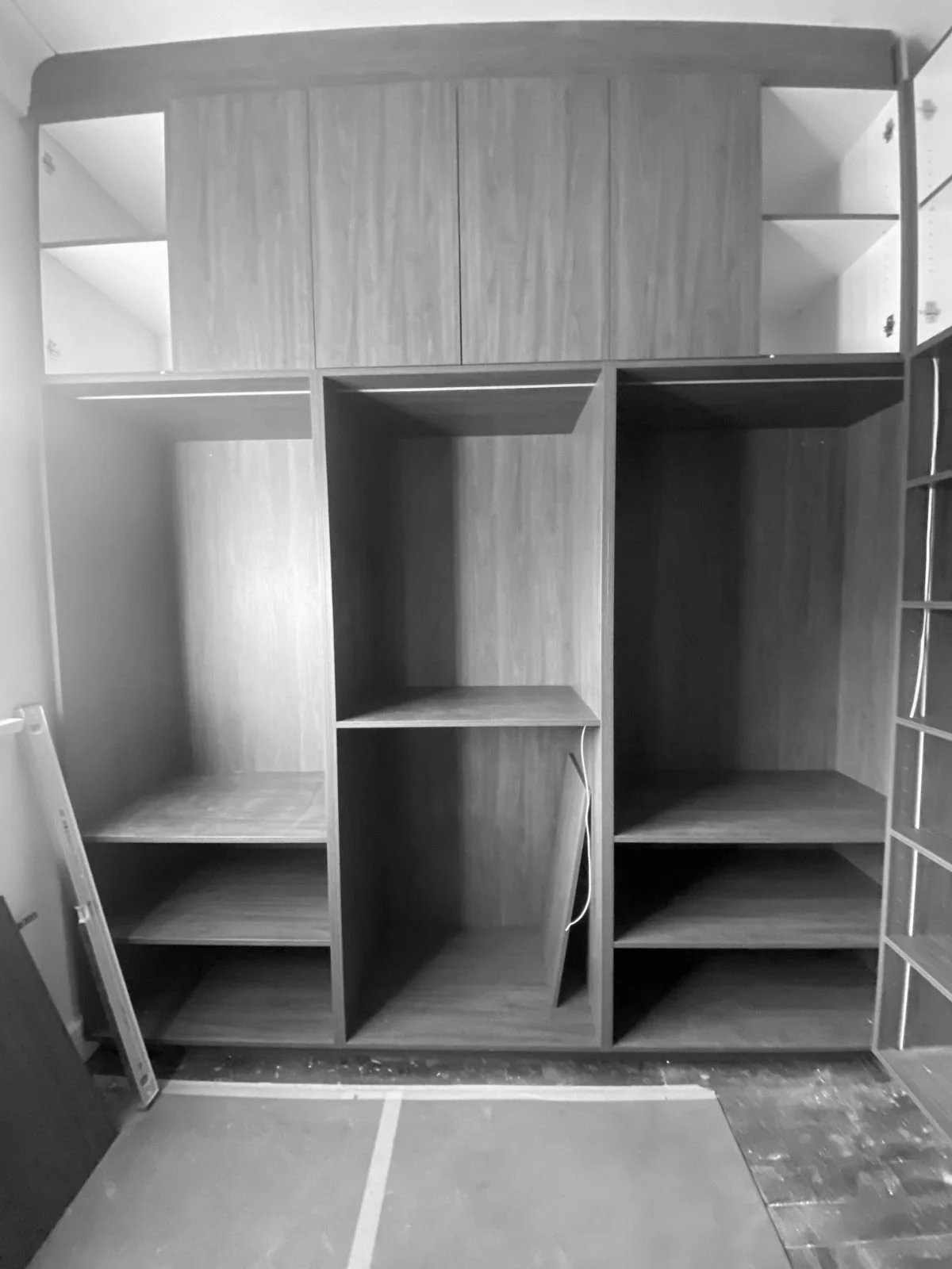 Walnut wooden closet with shelves and compartments, in a room under construction or renovation.