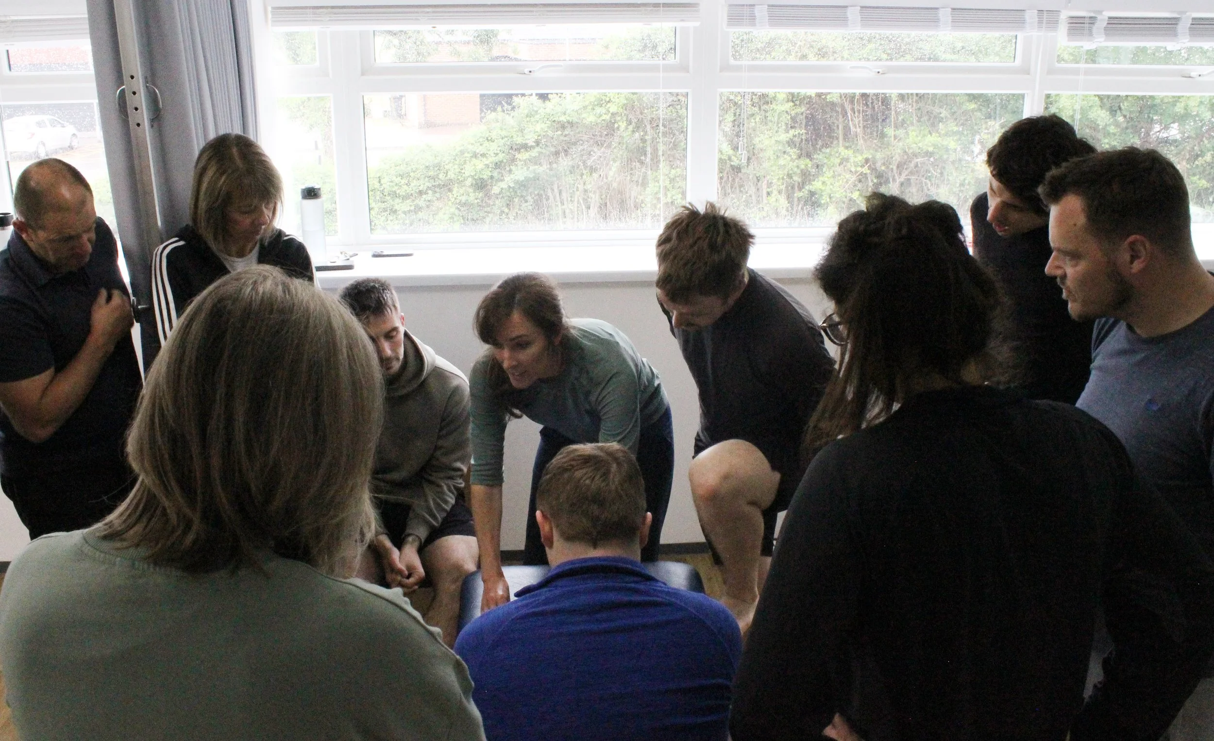 Group of people gathered near a window, engaged in a discussion or activity.