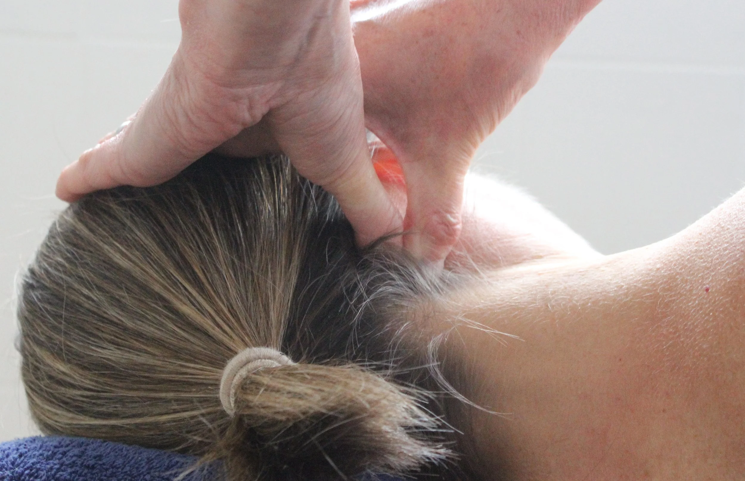 A person receiving a scalp massage or hair treatment, lying face down with their hair being gently massaged or brushed.