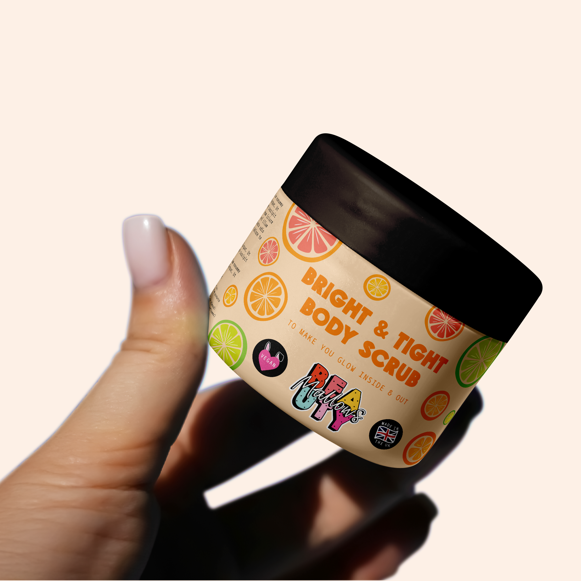 A hand holding a small container of bright and tight body scrub with a lemon print design, featuring vibrant citrus slices and label text that reads 'Bright & Tight Body Scrub' and various colorful stickers.