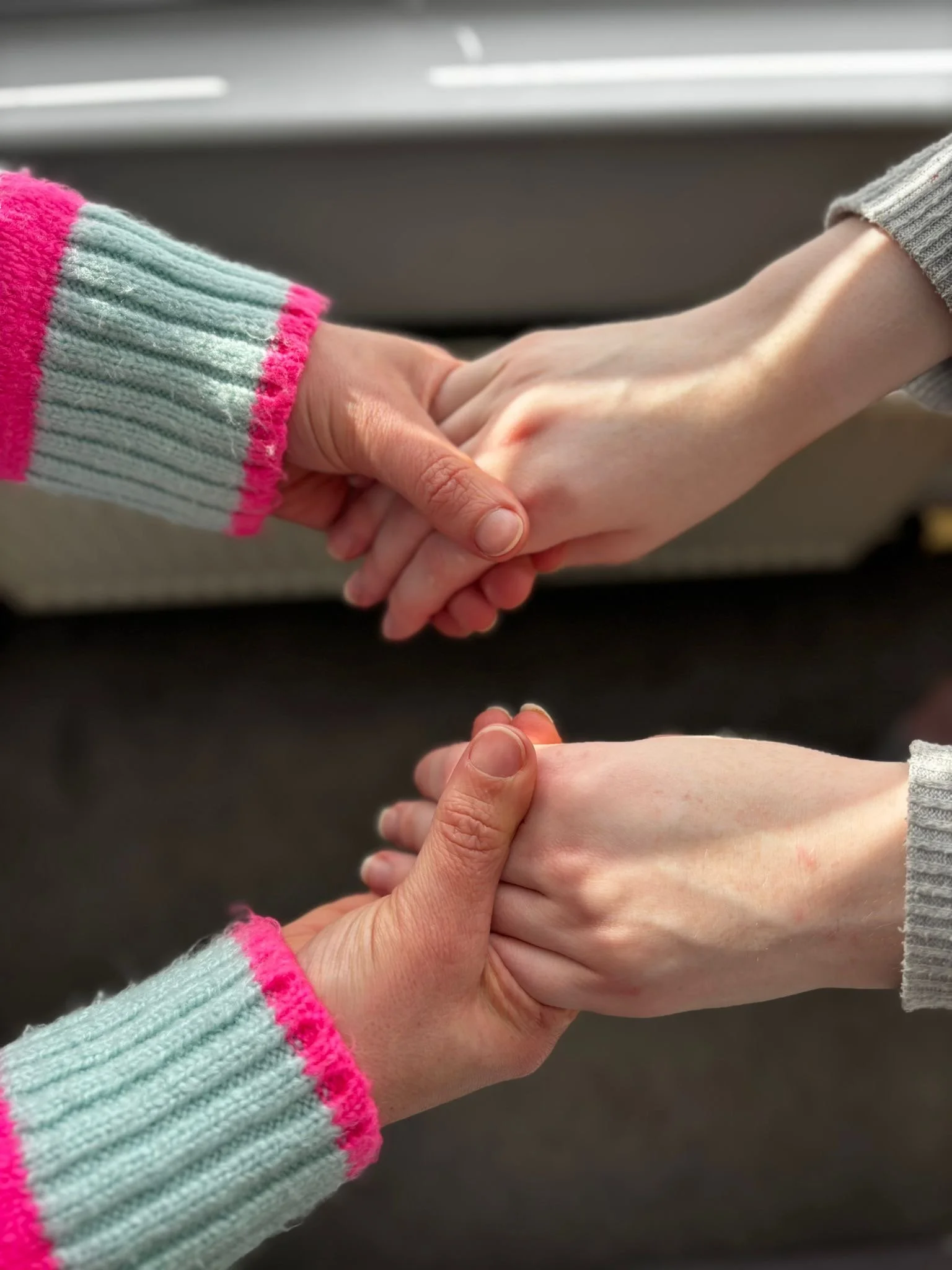 Two people gently holding hands, symbolising support, care, and connection.