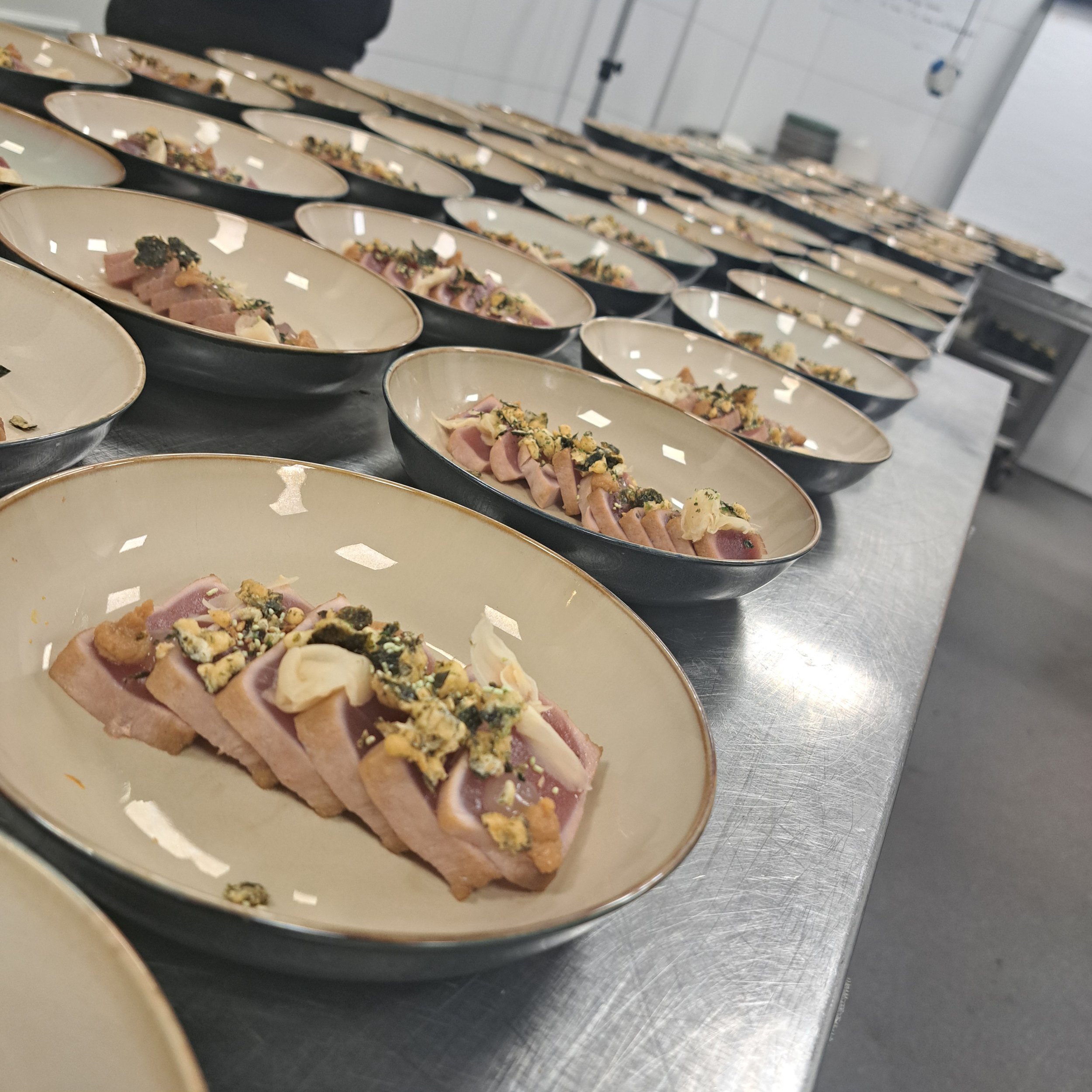 Rijen met kleine bordjes met eten in een keuken of restaurant.