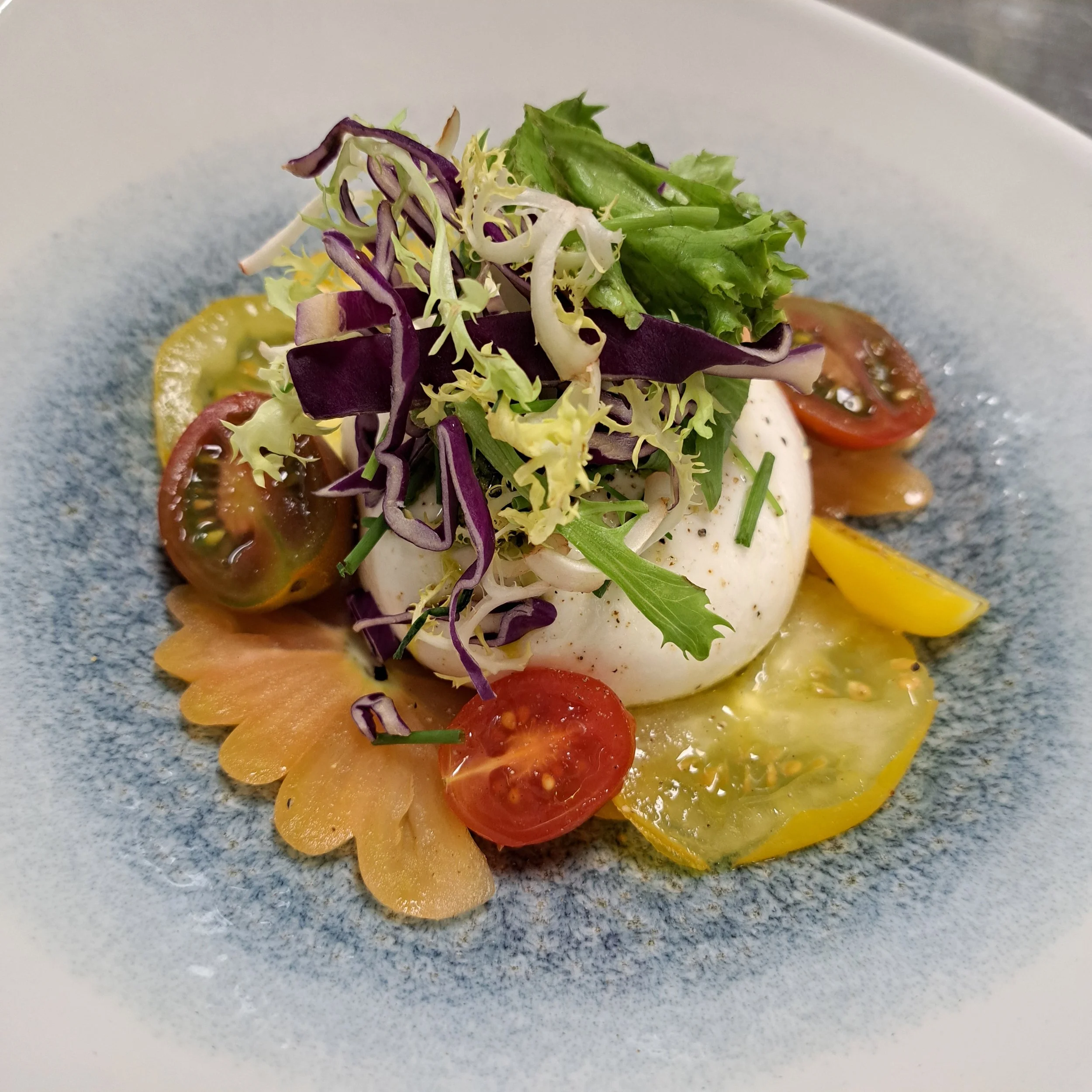 Burrata salade met hierloom tamaten en een kruiden salade.