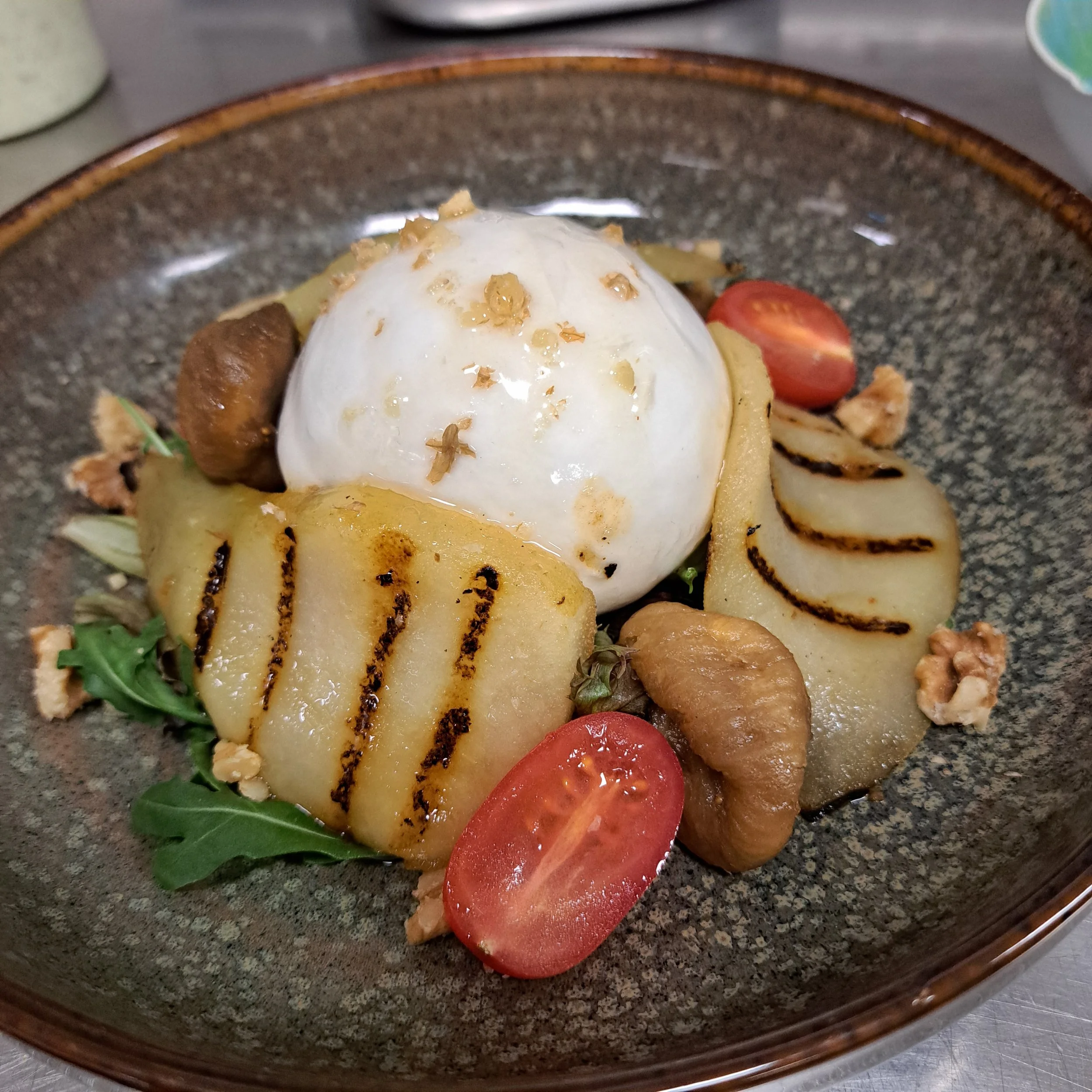 Salade burrata met gegrilde peer, cherry tomaten en tomaten crumble.