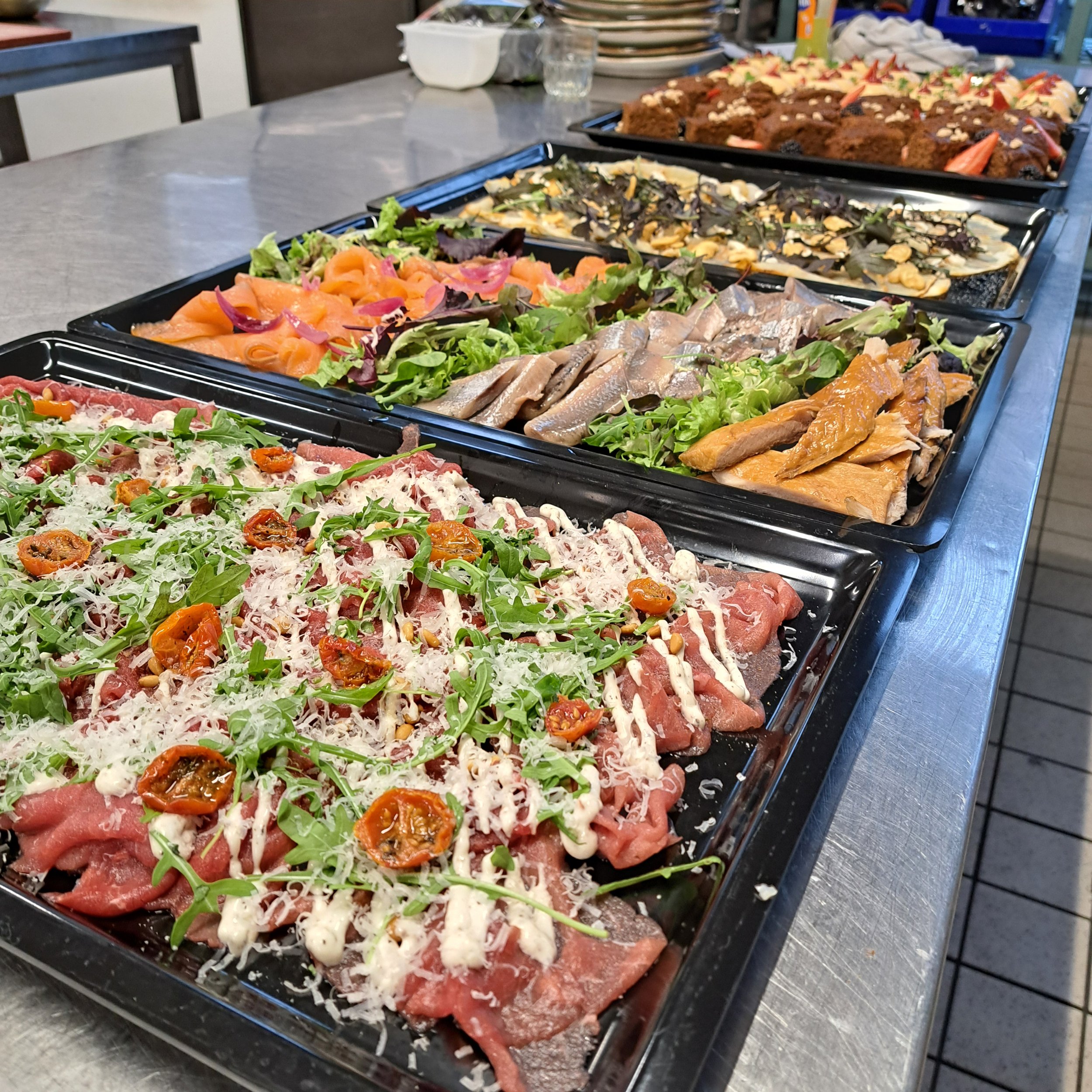 Verschillende kleurrijke salades en gerechten uitgestald op een buffet of tafel.
