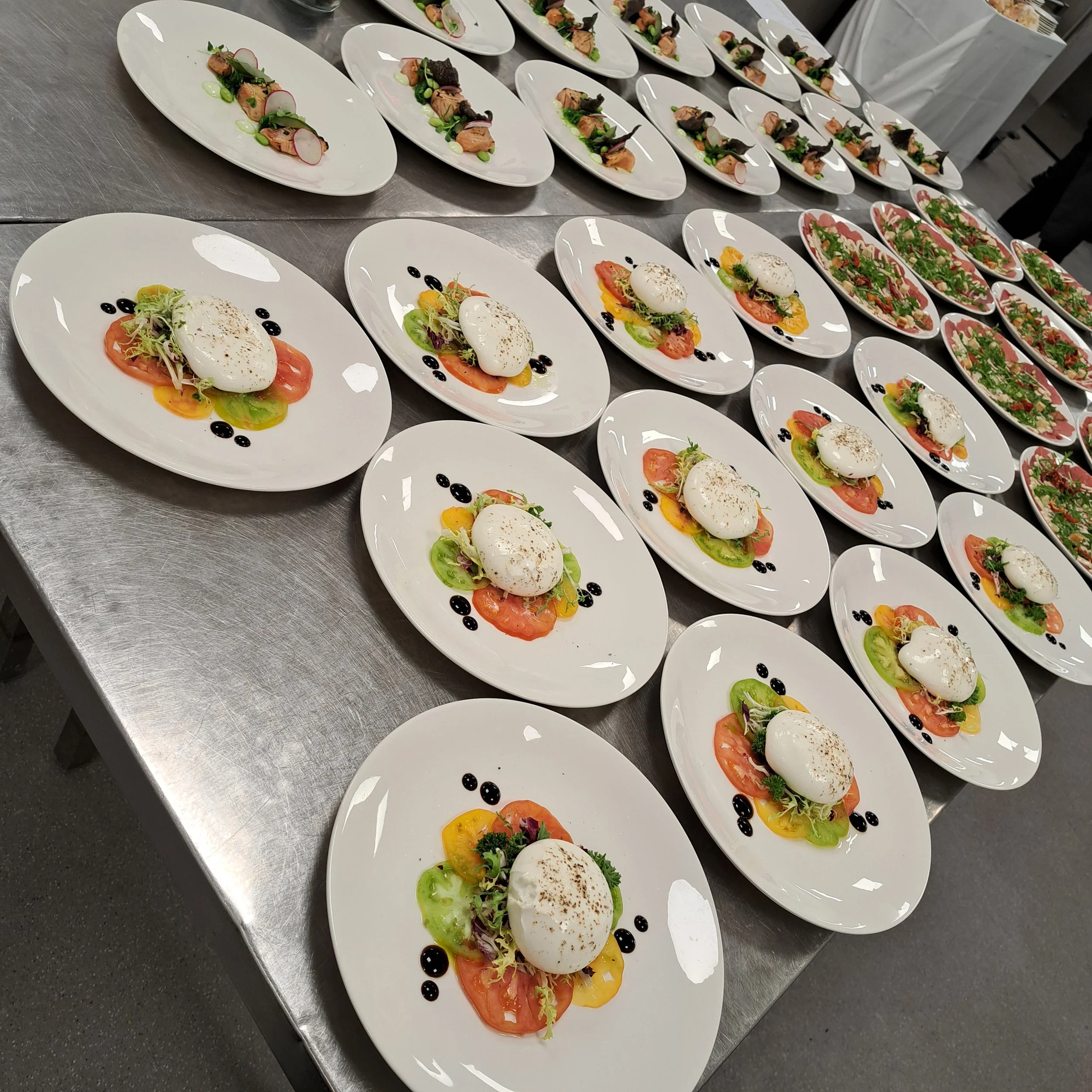 Assortiment van goutpreparaten met verschillende ingrediënten op witte borden, geserveerd op een metalen tafel.