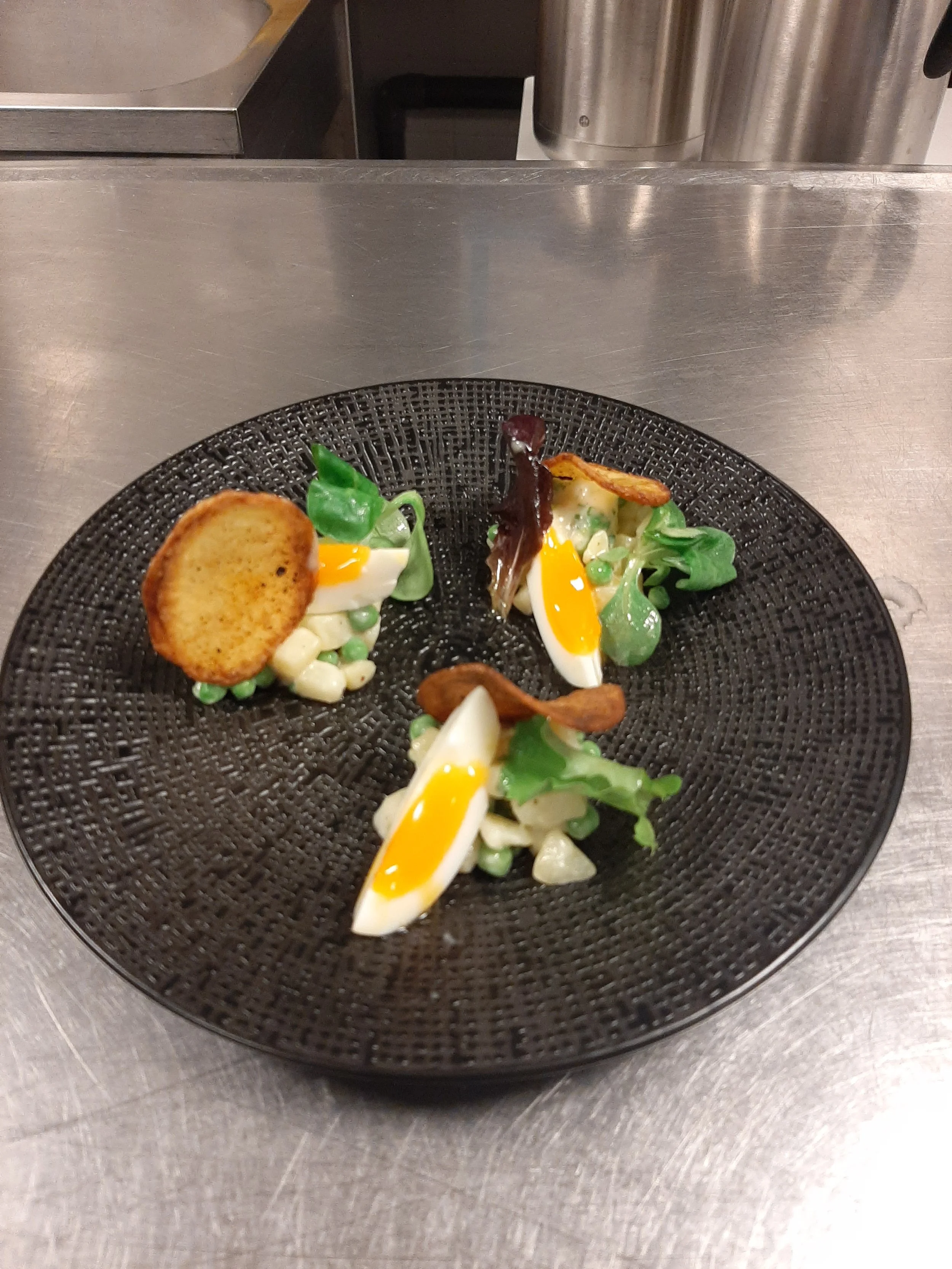 Gerecht met gepocheerd ei, spek, toast en diverse groenten op een zwart bord