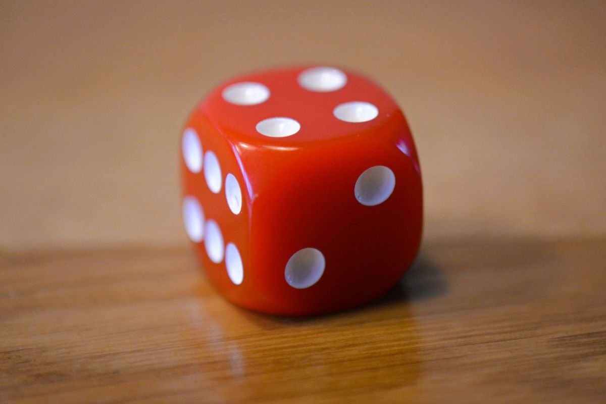 Roter 16‑mm‑Kunststoffwürfel mit weissen Augen von 1 bis 6 auf Holztisch.