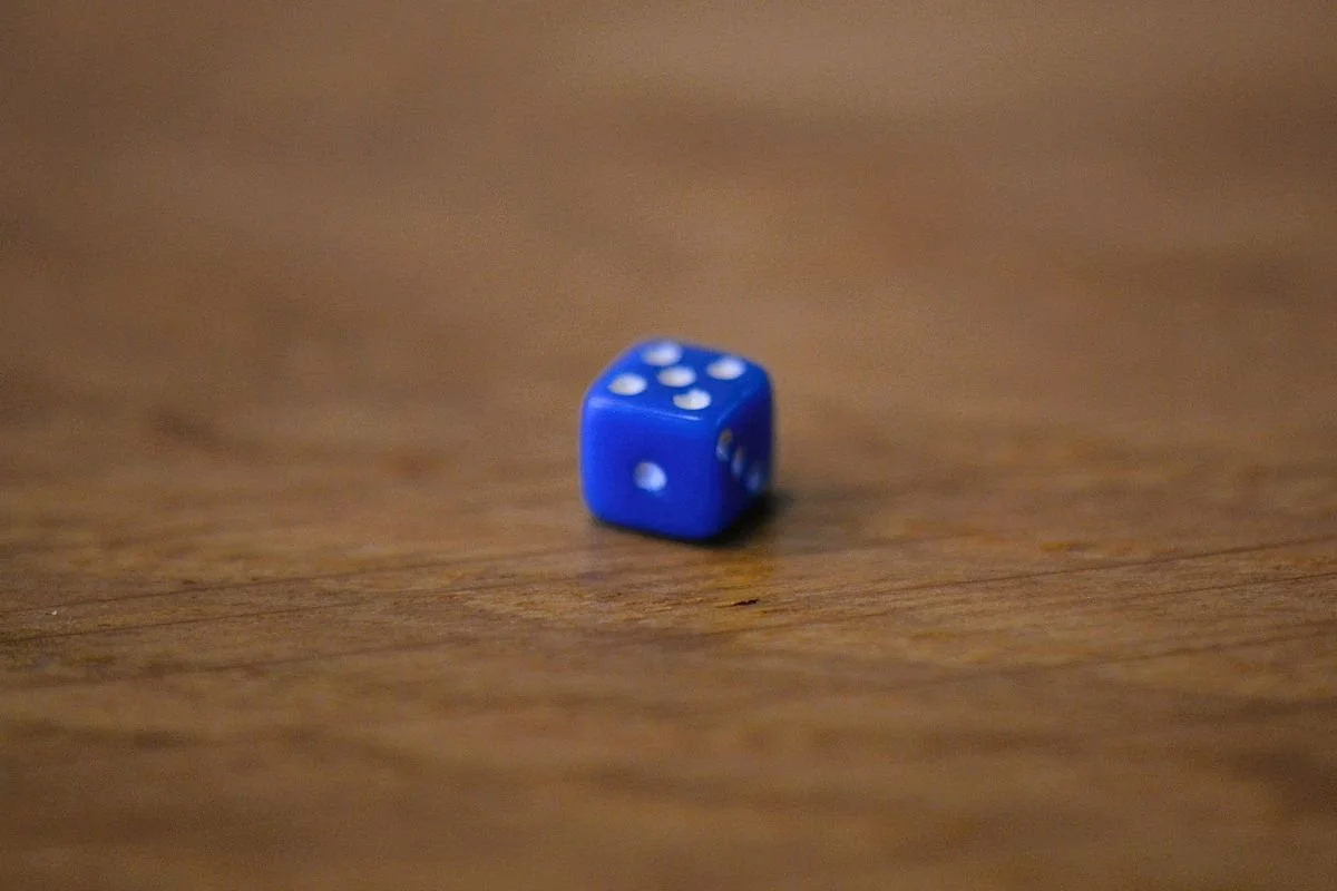 Blauer Miniatur‑Würfel 5 mm mit weissen Augen von 1 bis 6 auf Holztisch.