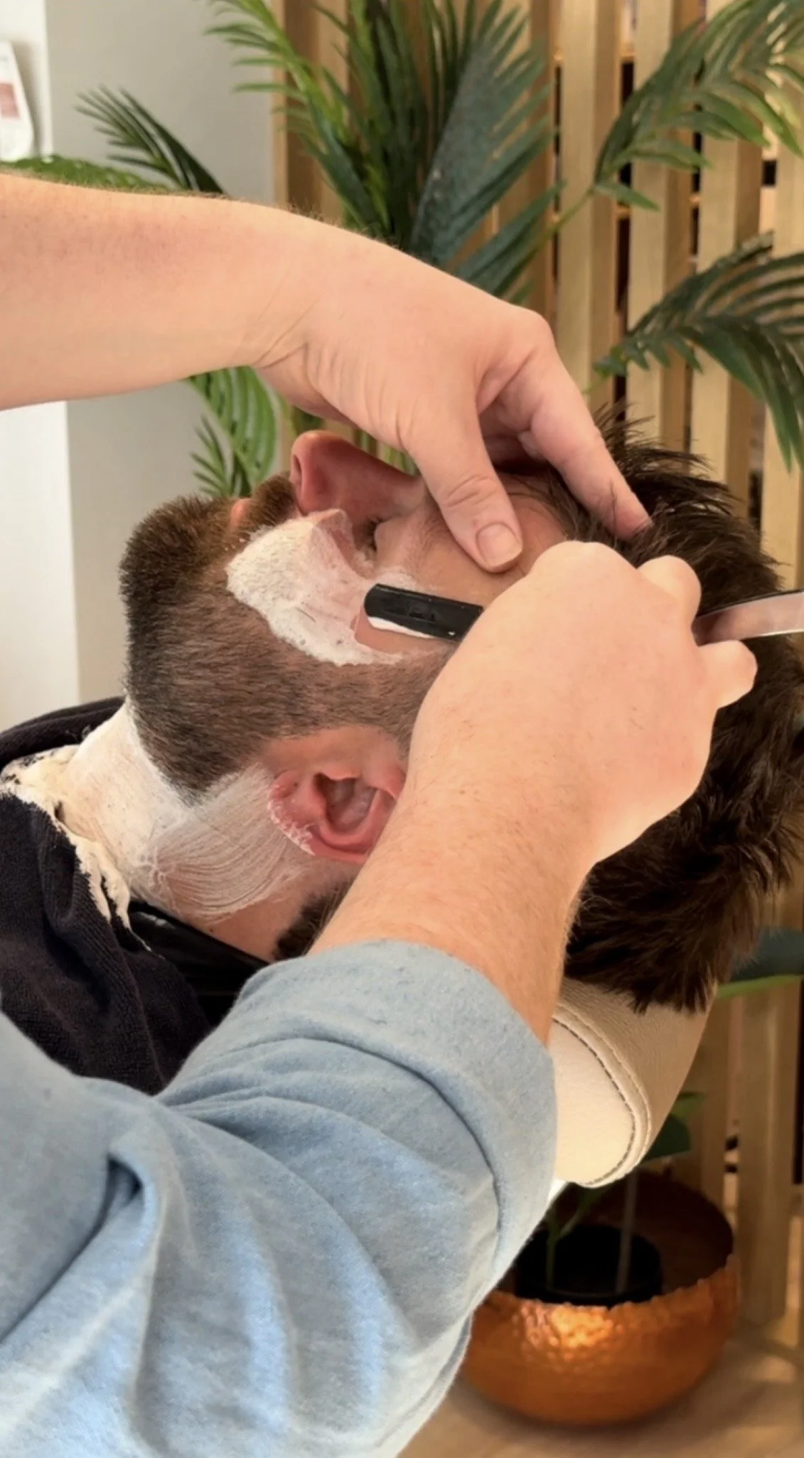Person getting a shave or beard trim from a barber.