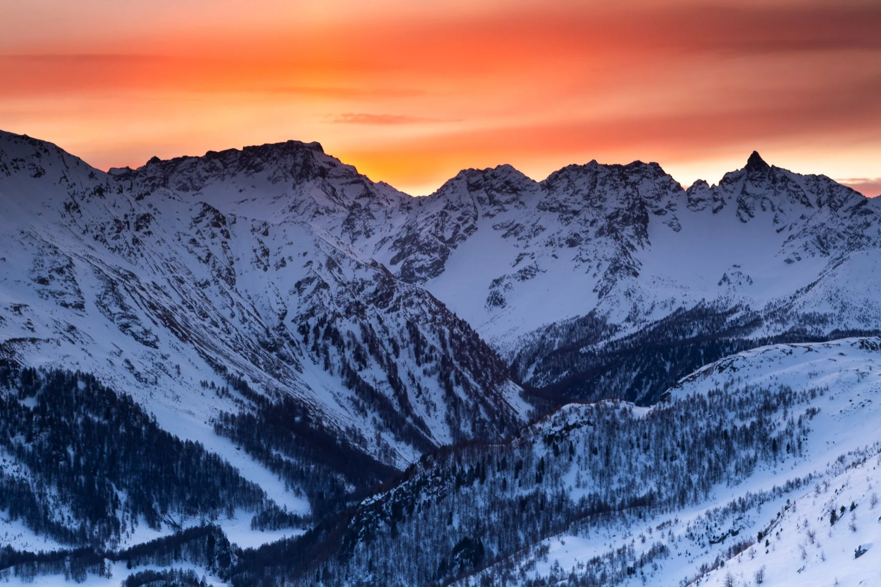 Snow-covered mountain peaks at sunset with a colorful sky