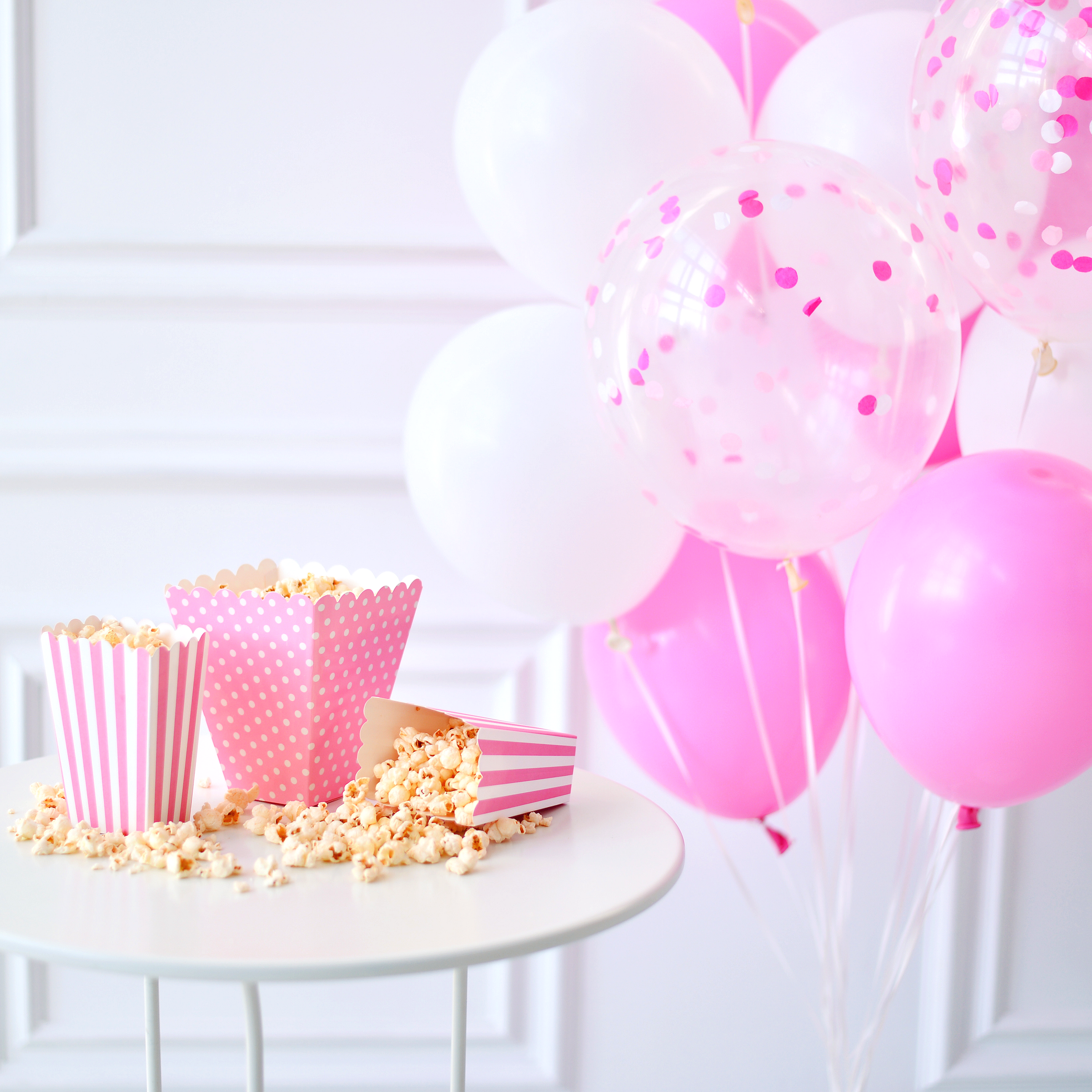 Pink and white themed birthday party with pink balloons, pink popcorn containers, and pink accents.