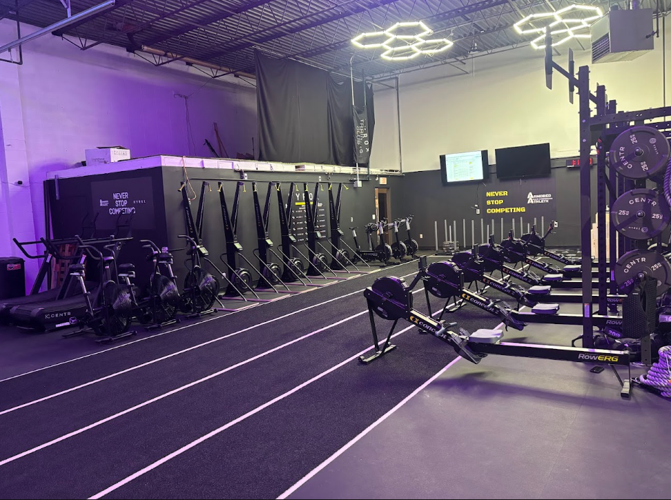 Inside armored athlete hyrox training club with rowing machines, assault bikes, and weightlifting equipment.