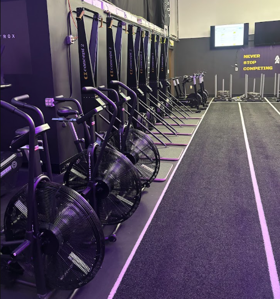 Row of air bikes and resistance machines in a gym with motivational posters and large screens at armored athlete hyrox training club milwaukee