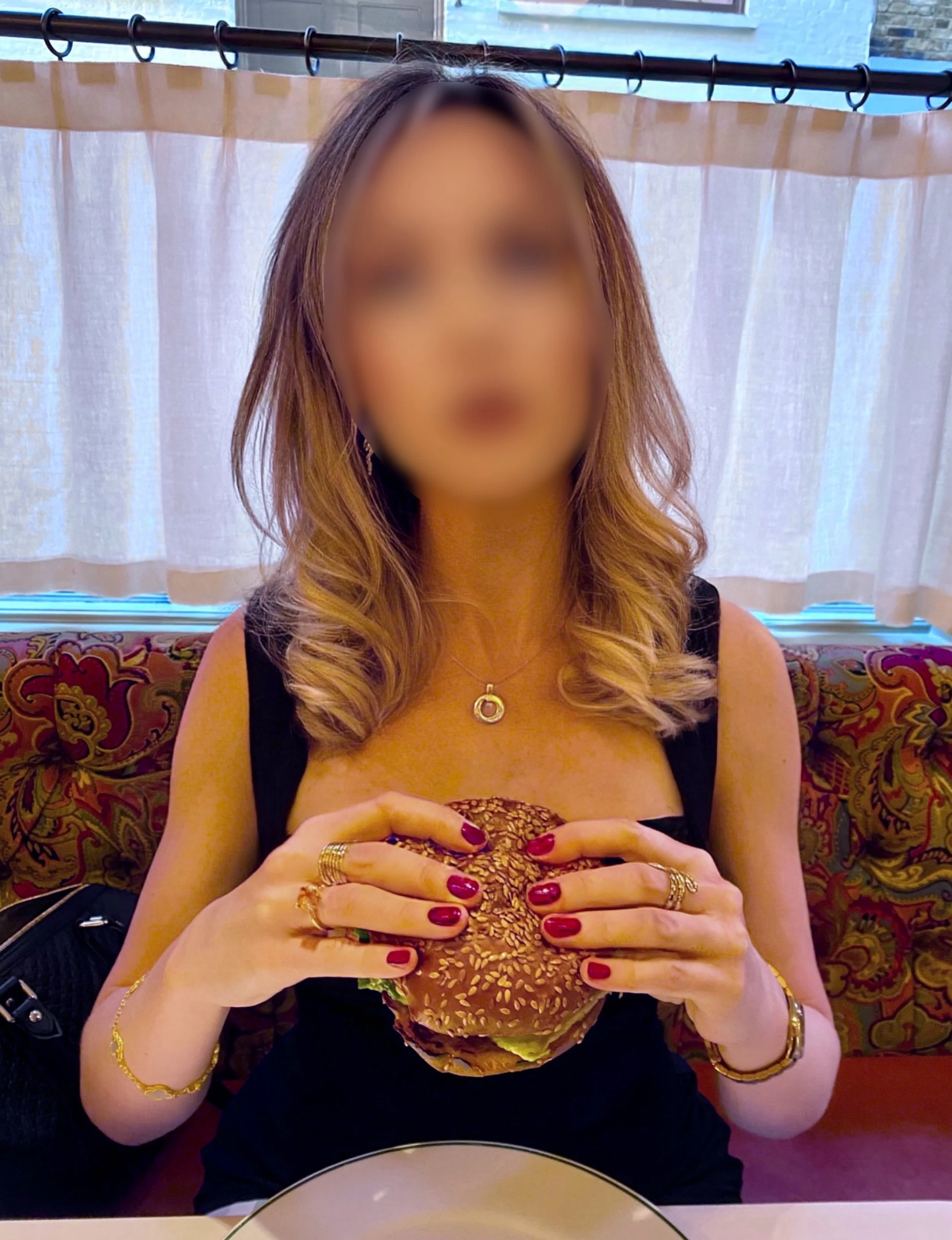 Blonde high class independent London escort holding a hamburger at The Ivy.