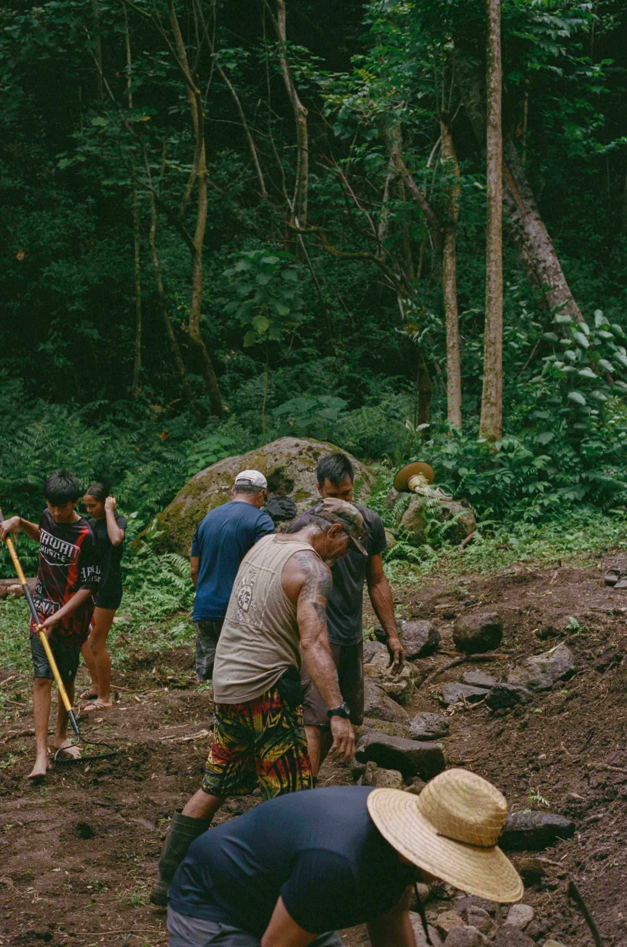 Group of people working on constructing a stone pathway in a lush, green forest.