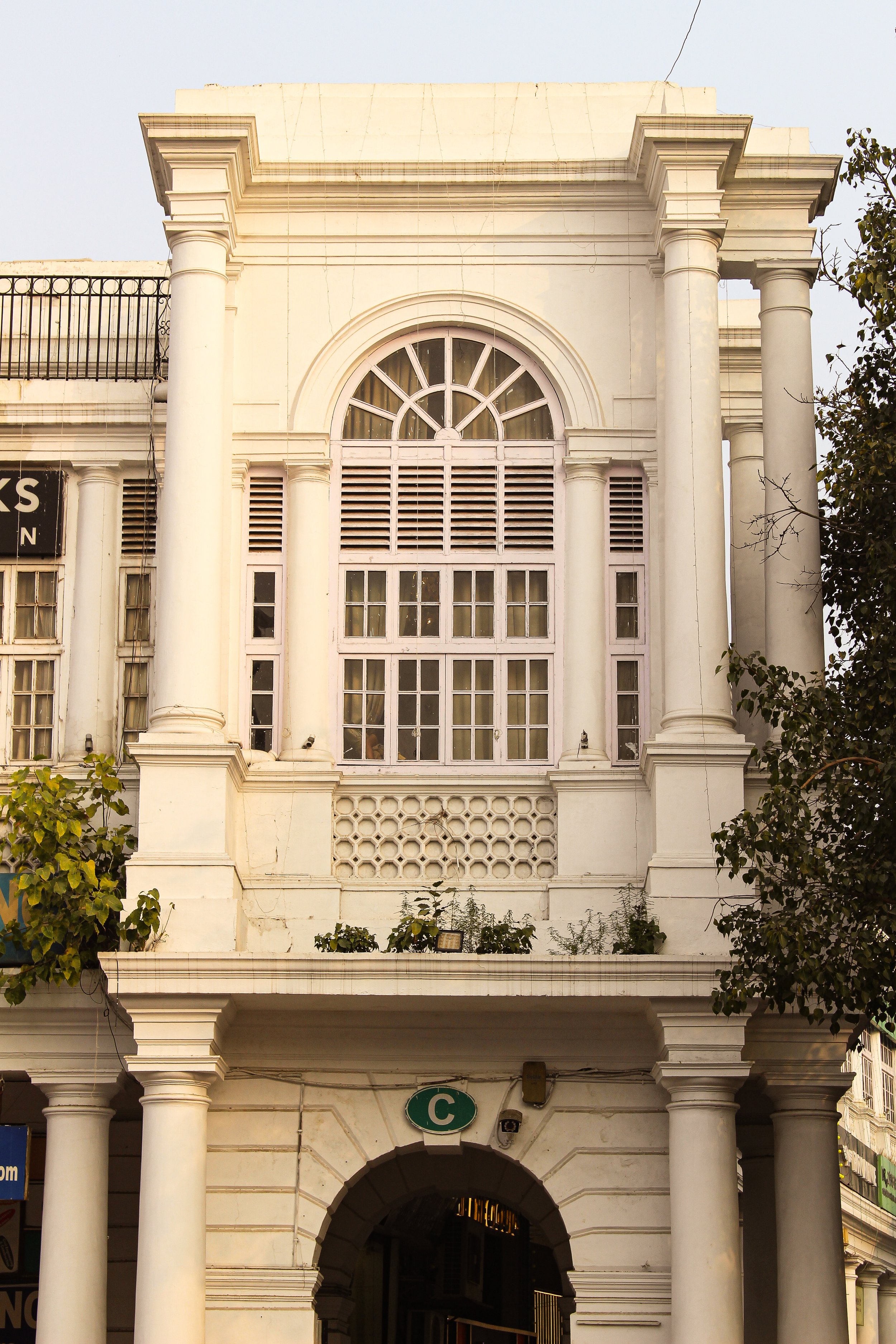 White colonial-style building with large arched window, columns, and decorative elements.