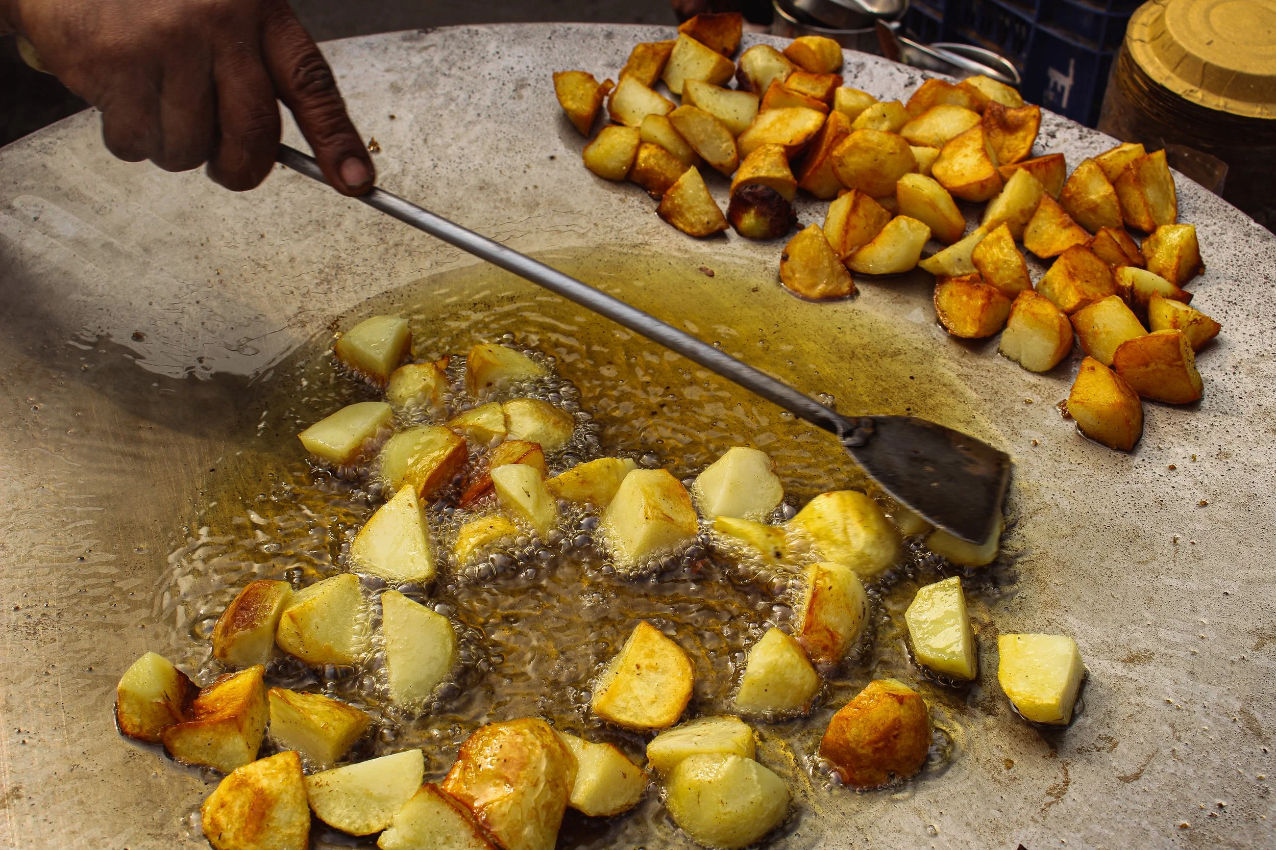 Person frying diced potatoes on a griddle.