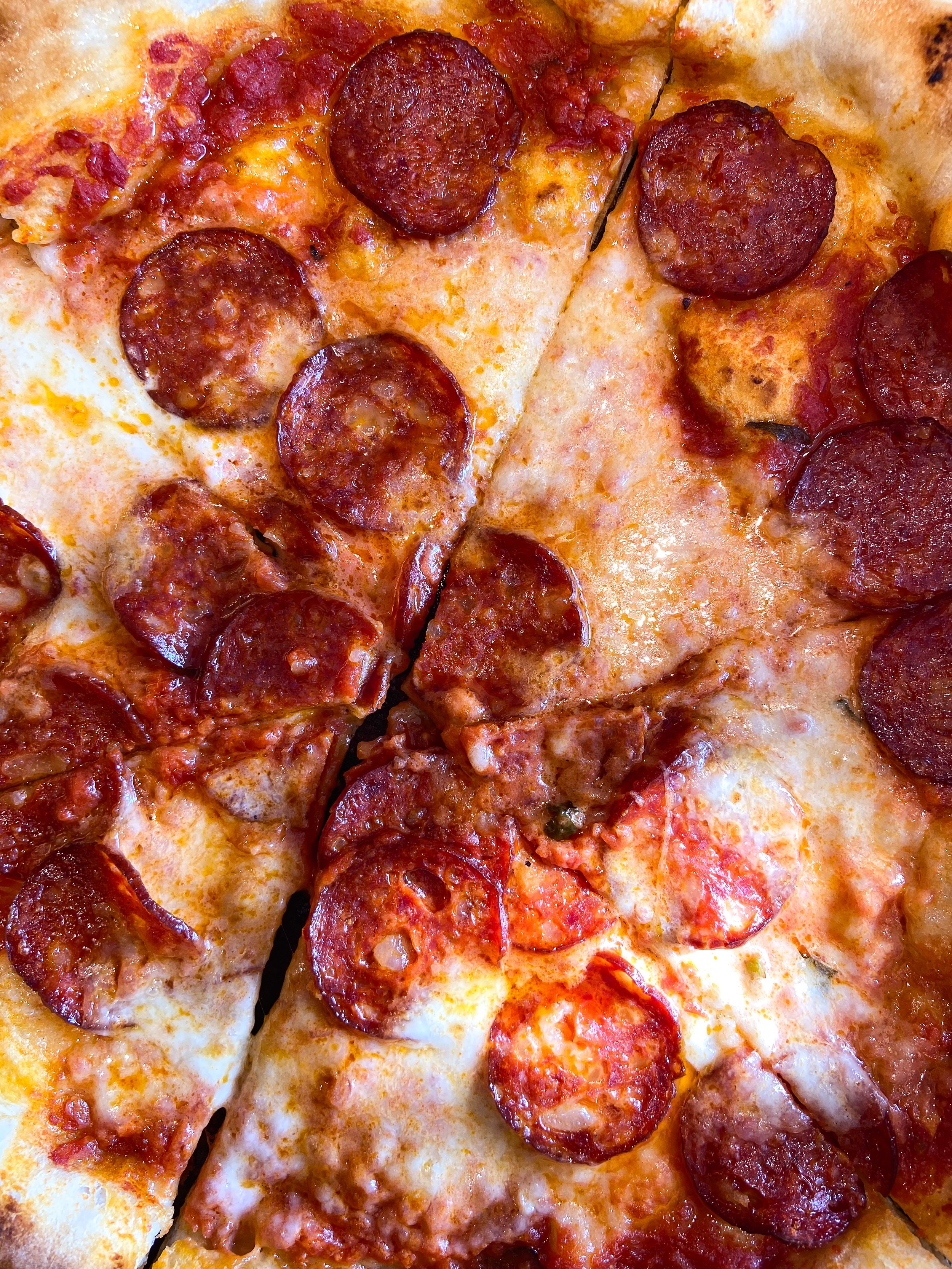 Close-up of a pepperoni pizza with a few slices cut out, showing melted cheese and pepperoni slices.
