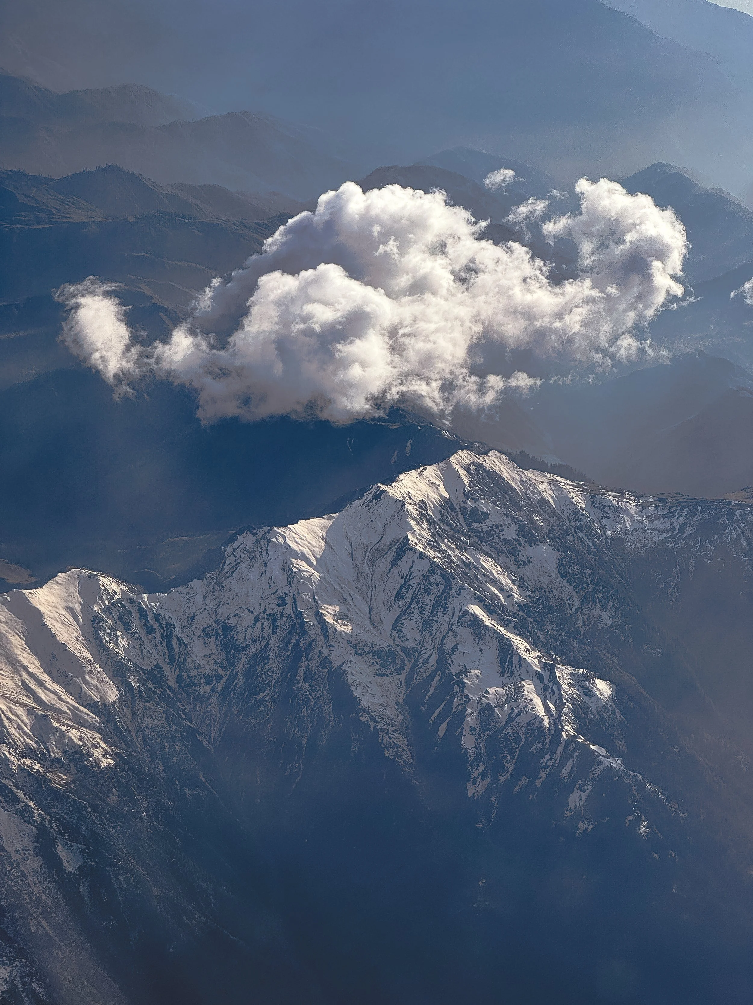 Snow-capped mountain range with a large cloud formation above.