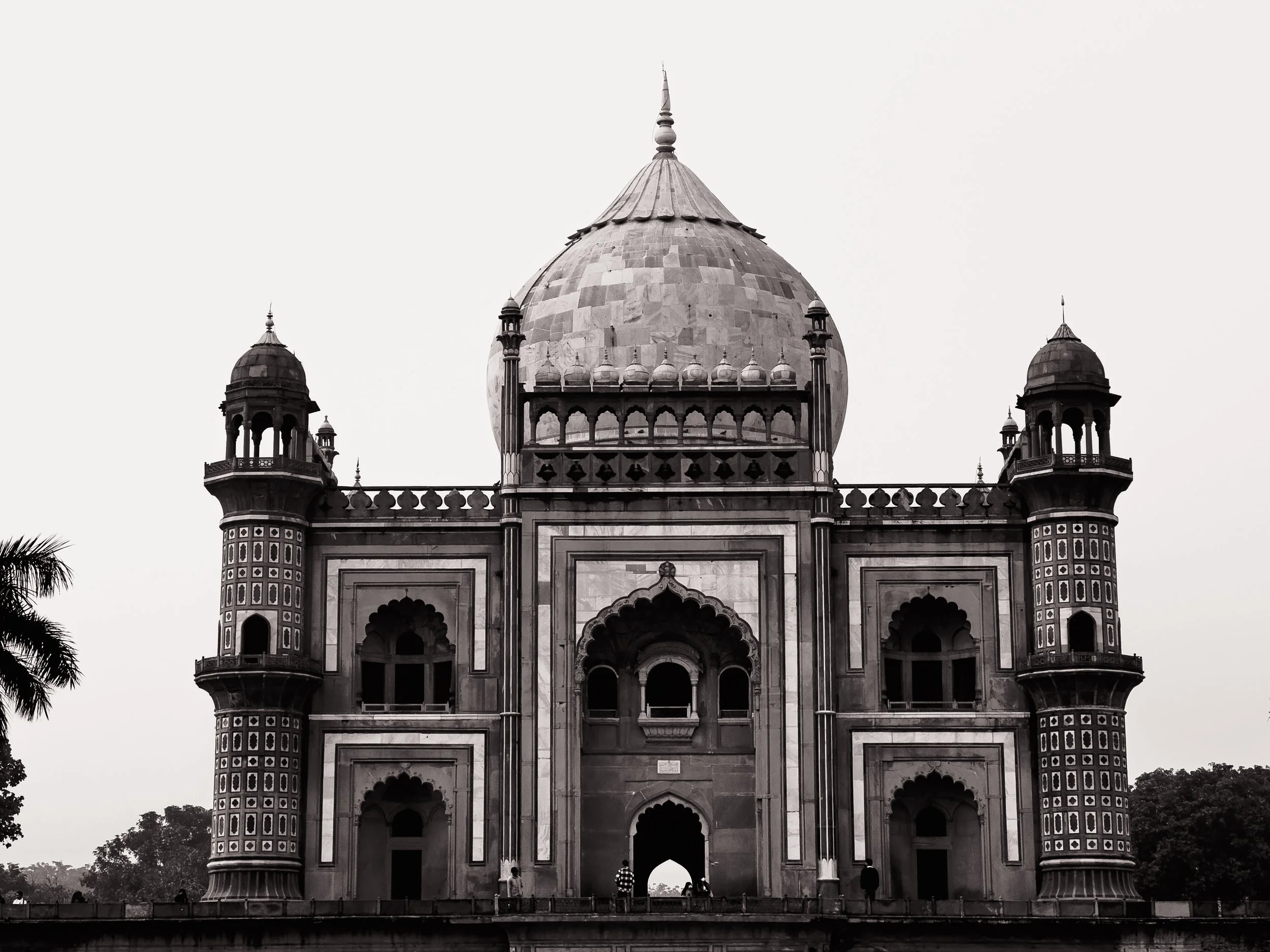 Black and white photo of the Taj Mahal, an iconic Mughal architecture mausoleum in India, featuring a large central dome, four minarets, and detailed arches.