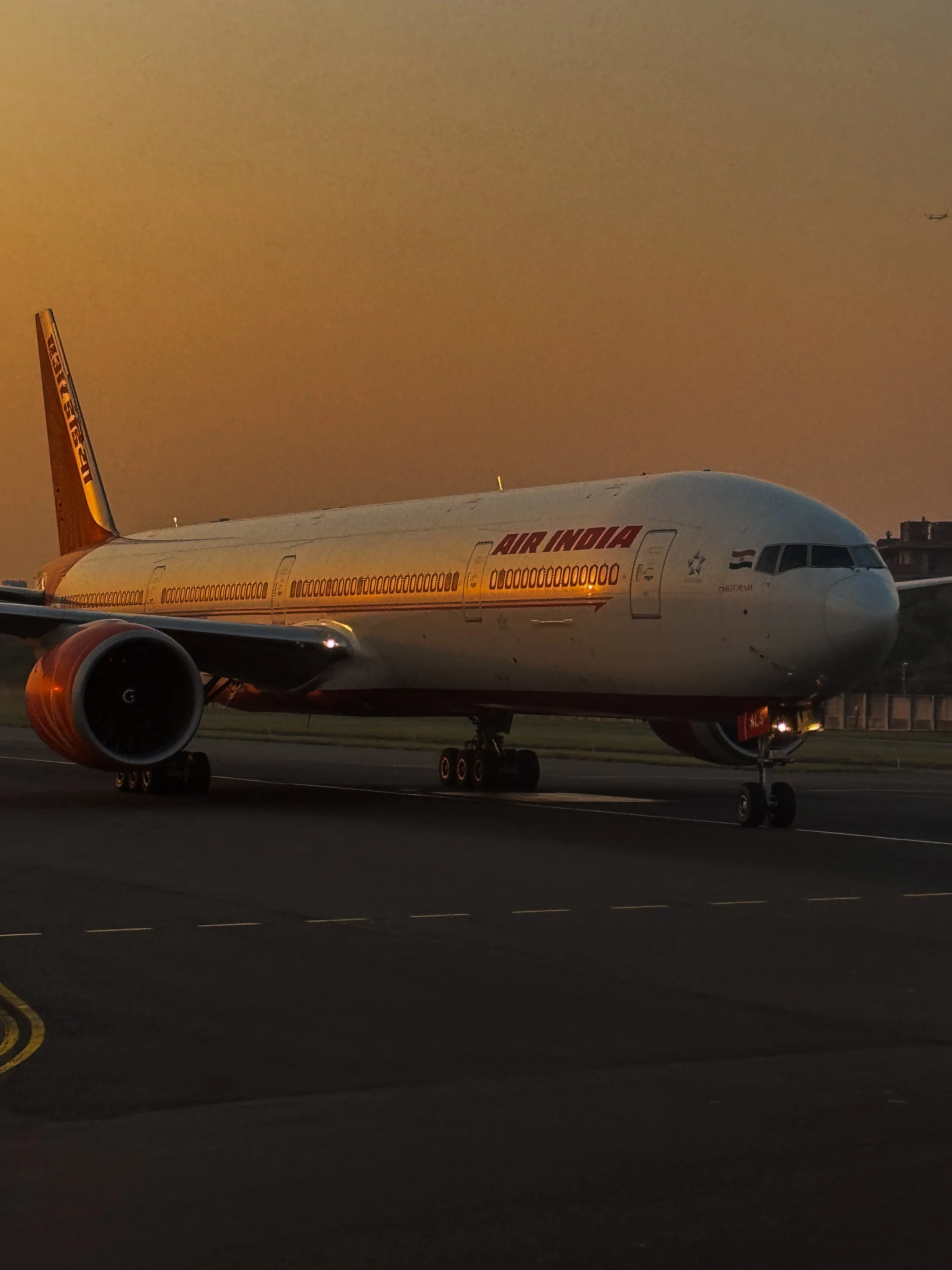 An Air India airplane parked on the runway at sunset.