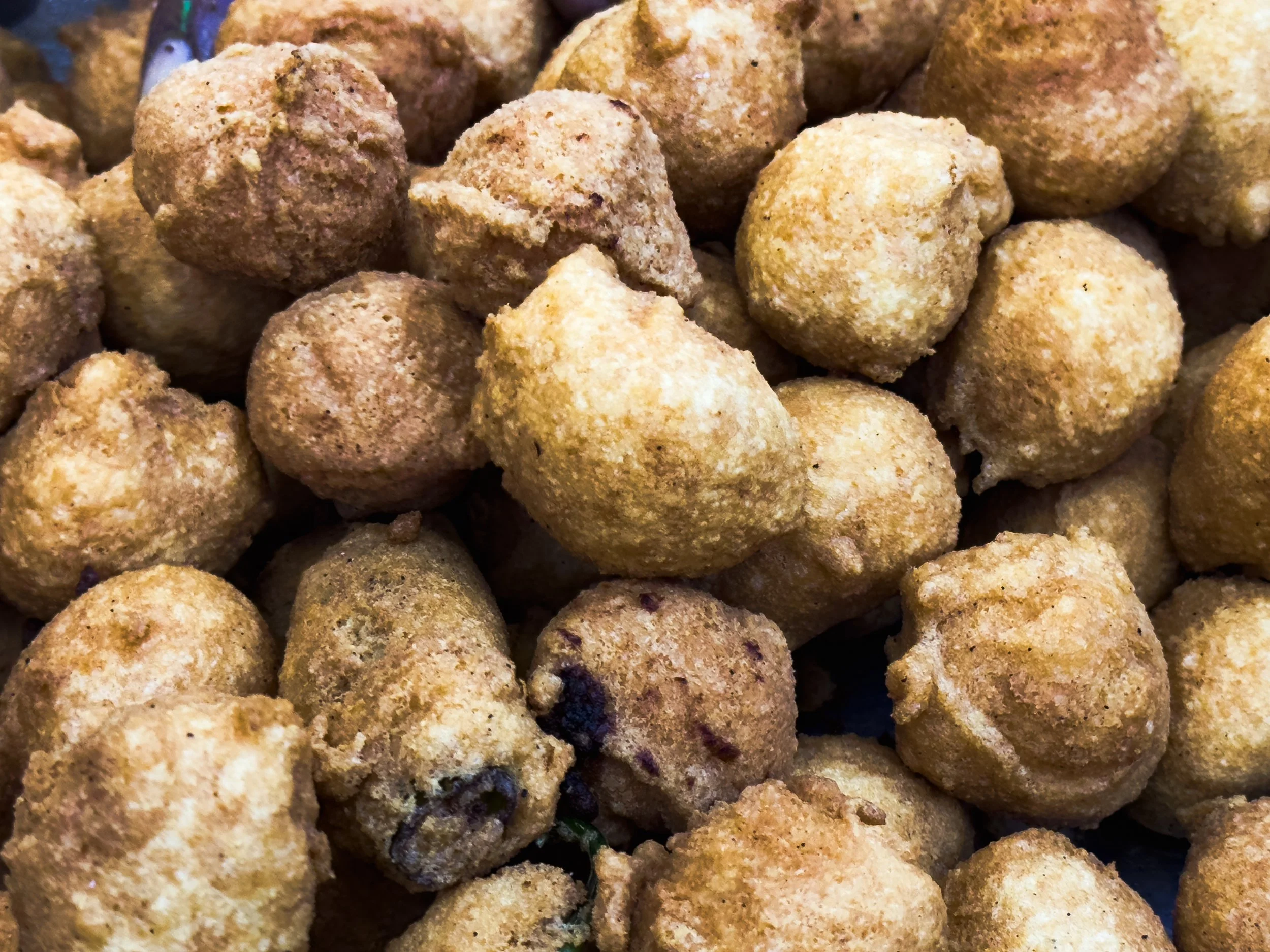 Close-up of multiple fried food balls, golden-brown in color, some with dark spots.