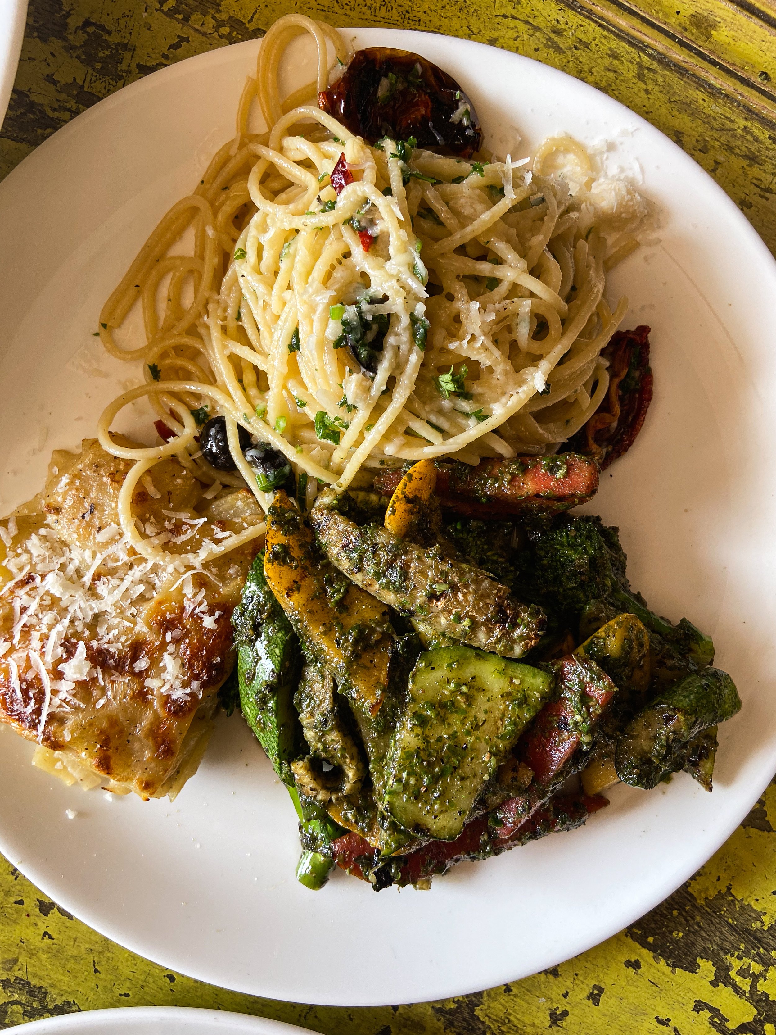 Plate of Italian food with pasta, eggplant, and a lasagna serving, garnished with cheese and herbs.