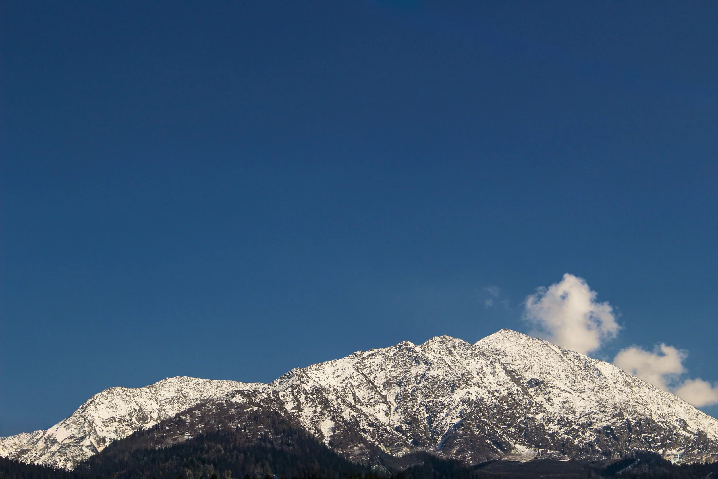 Snow-capped mountain range under a blue sky with some clouds.