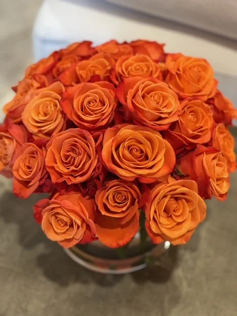 A bouquet of orange roses arranged in a container.