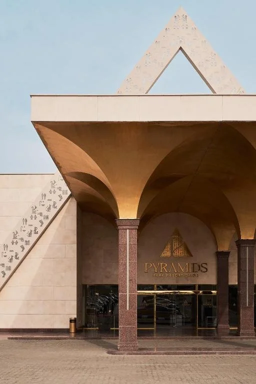 Exterior view of the pyramids-themed resort entrance with gold archways and a pyramid structure on top.