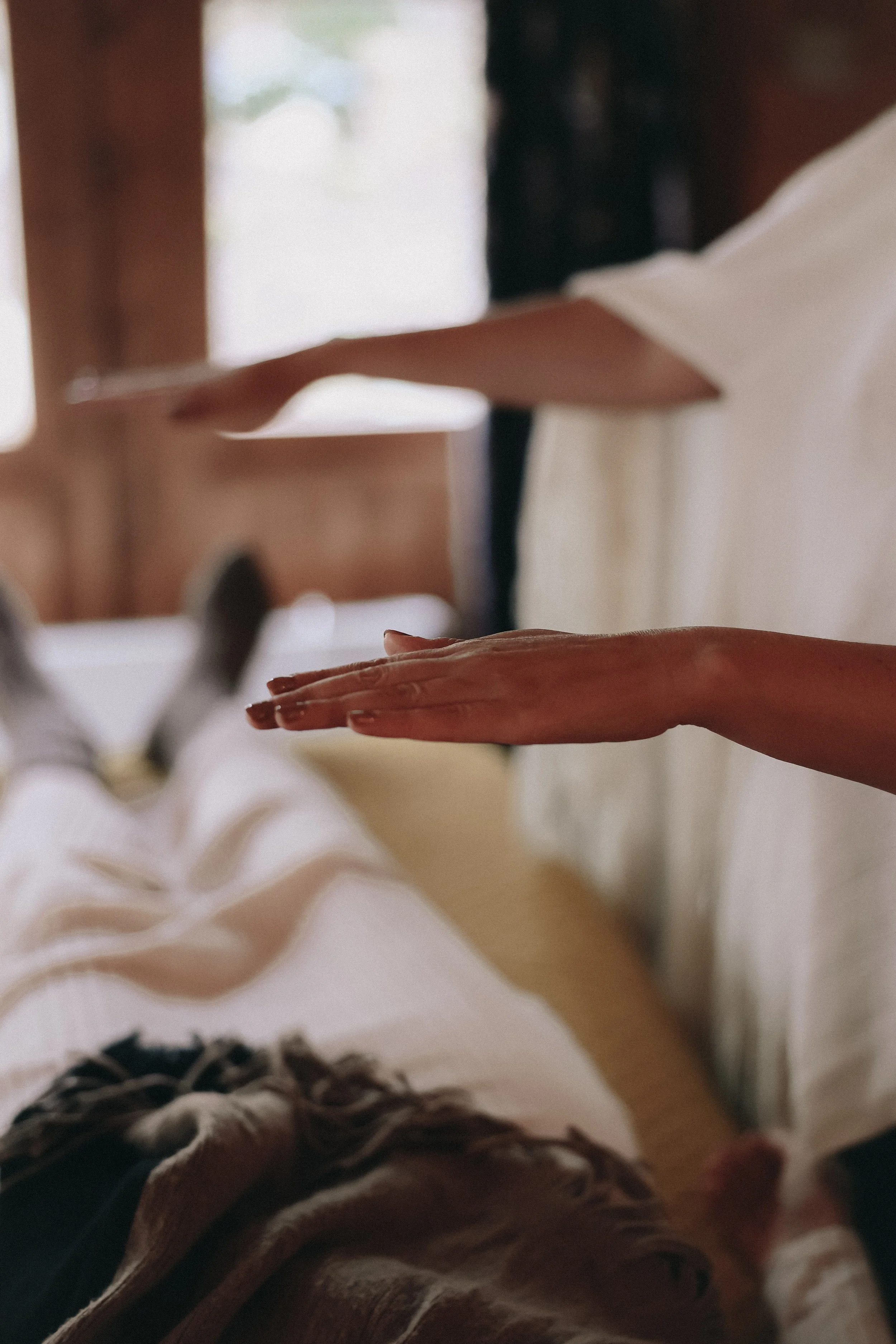 Close-up of a person's hand resting on a white surface, with other hands visible in the background.
