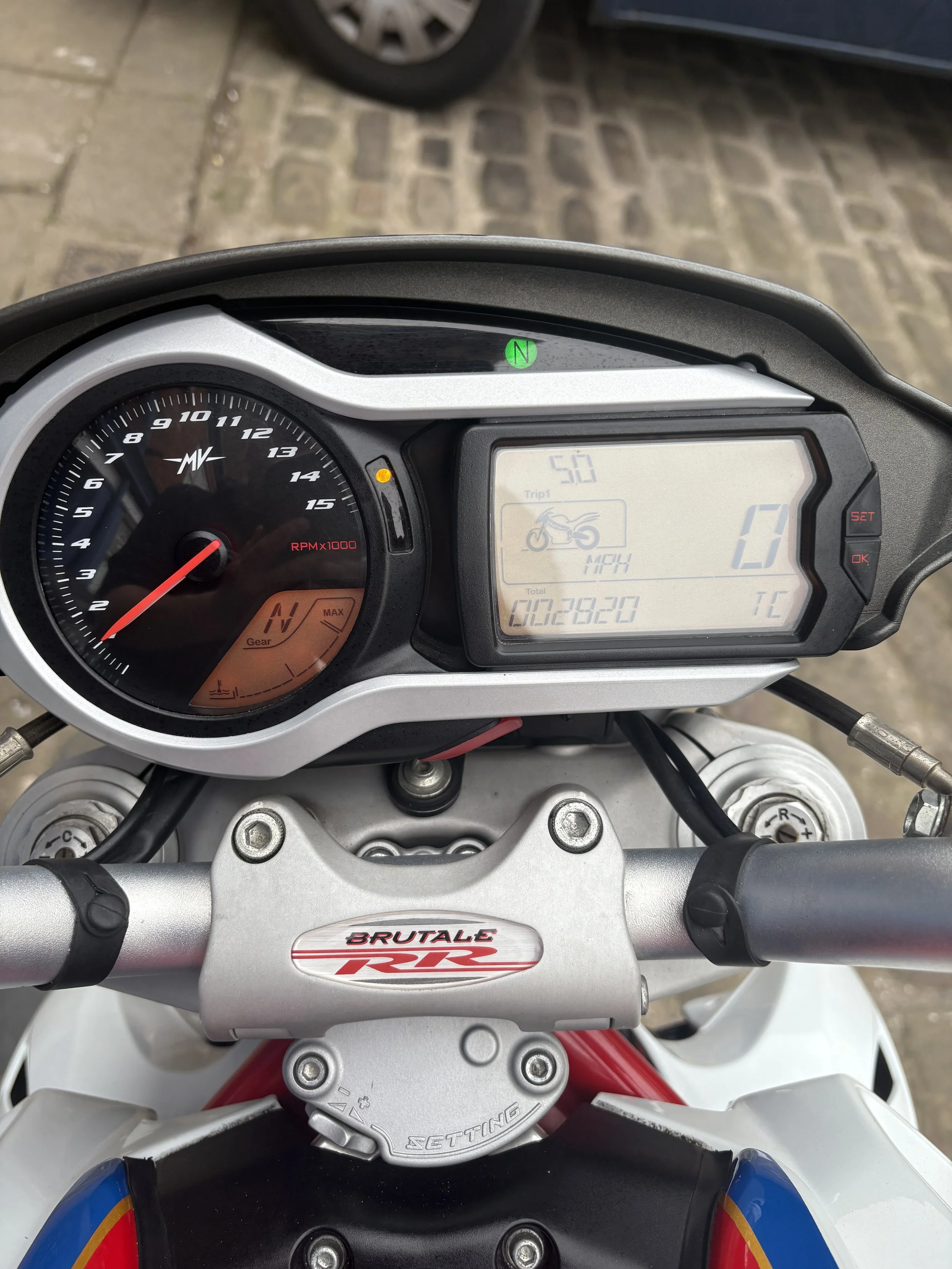Motorcycle dashboard showing digital speed of 17 mph, tachometer reading approximately 1,000 RPM, total mileage of 28,220 miles, and green neutral indicator light.