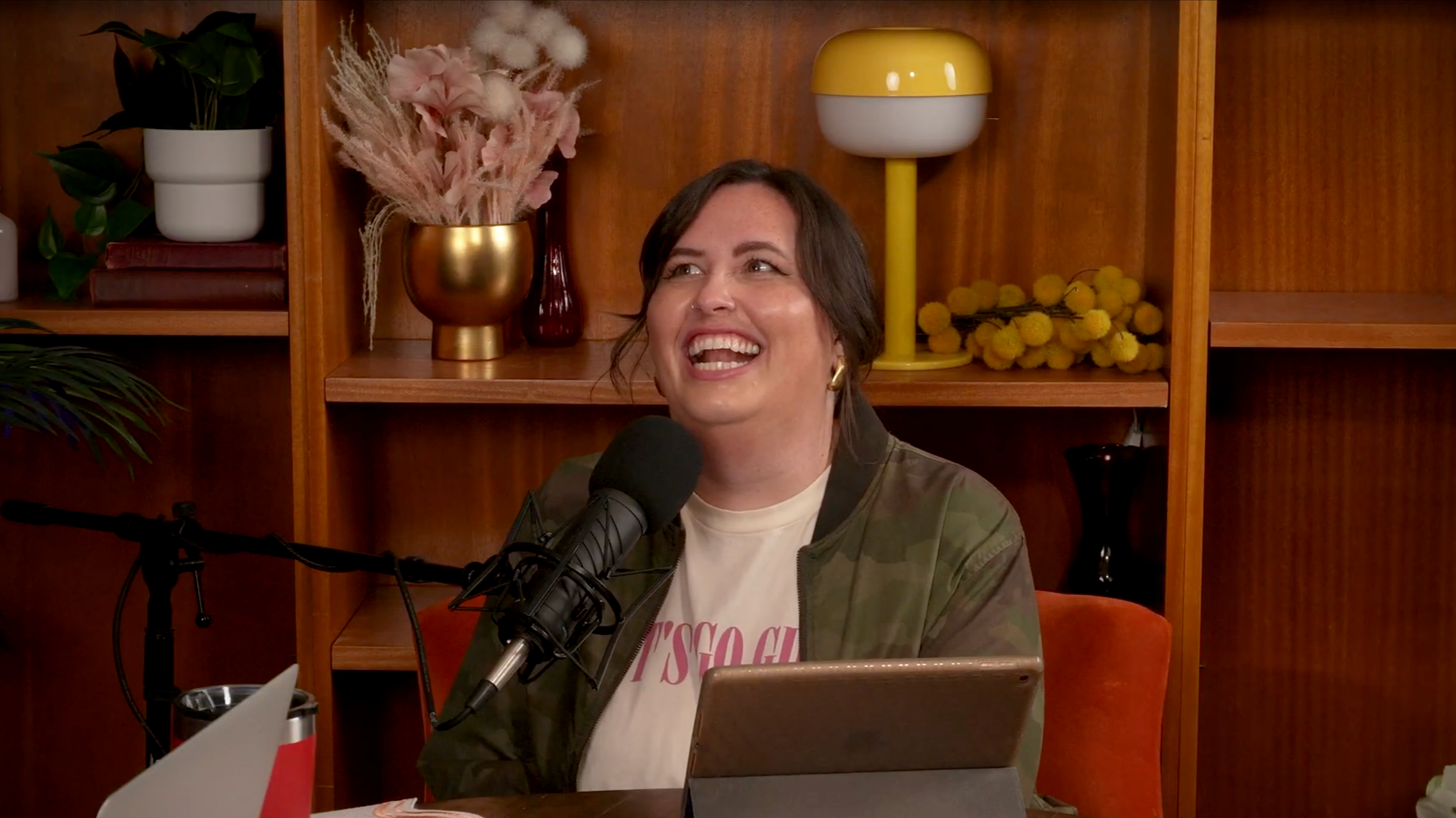 Ashley - podcast host has short brown hair and is sitting in the studio in front of her laptop and microphone.