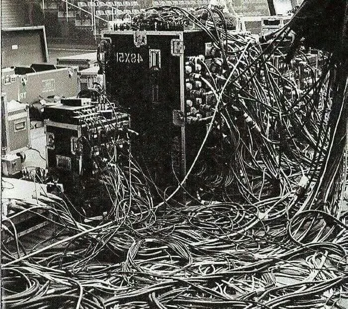 Blurred image showing numerous cables and electronic devices used for music production.