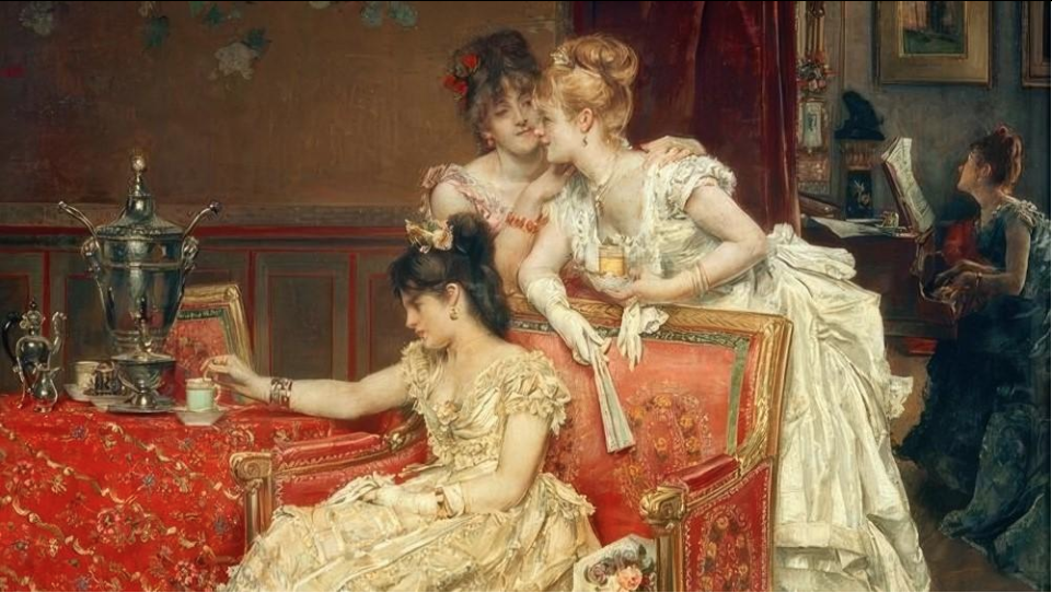 Three women in elegant, vintage dresses are interacting in a richly decorated room. One woman is sitting at a table reaching for a small item, while the other two are leaning over a sofa, engaging in a conversation.