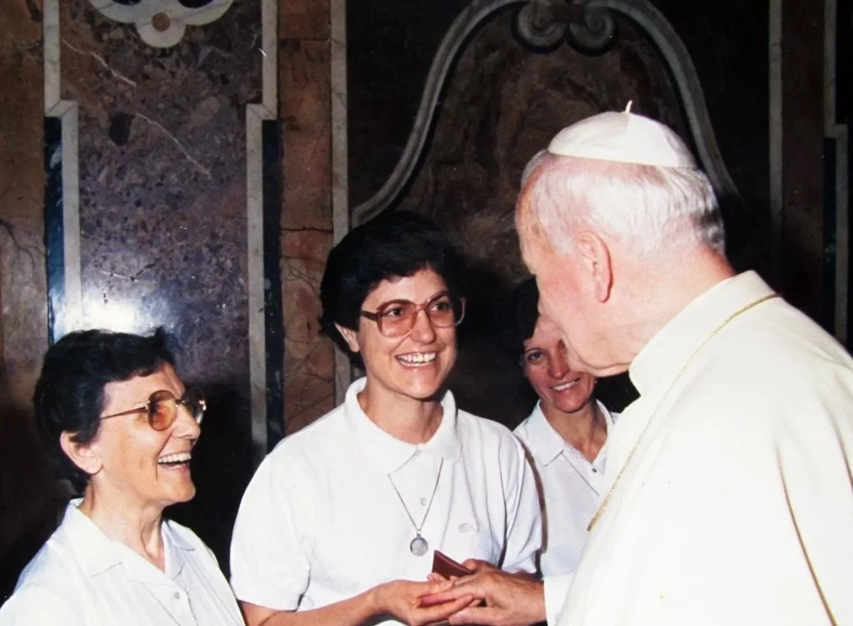 Le pape rencontrant trois femmes, toutes souriantes, dans un cadre intérieur, probablement lors d'une cérémonie ou rencontre officielle.