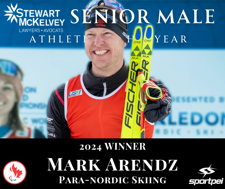 A male athlete smiling and holding yellow Fischer skis, wearing a black headband, red sports vest, and black gloves, standing in front of a blue background with text honoring his 2024 win.