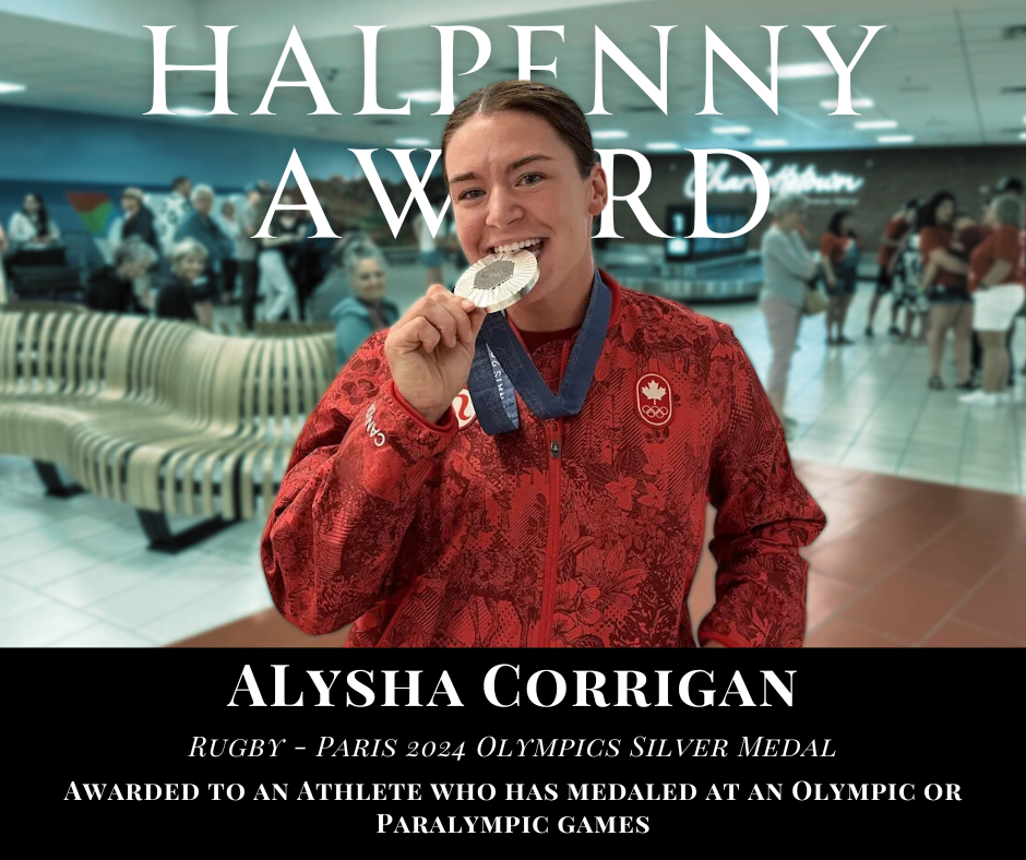 A young woman in a red sports jacket is holding a silver medal in her hand and smiling at the camera in an airport terminal. The text on the image reads 'Halpenny Award Alysha Corrigan Rugby - Paris 2024 Olympics Silver Medal.'