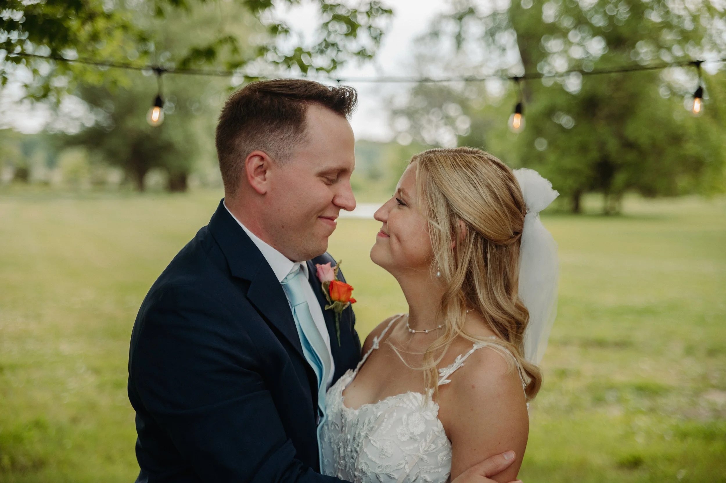 A newlywed couple smiling and gazing into each other's eyes outdoors during their wedding.