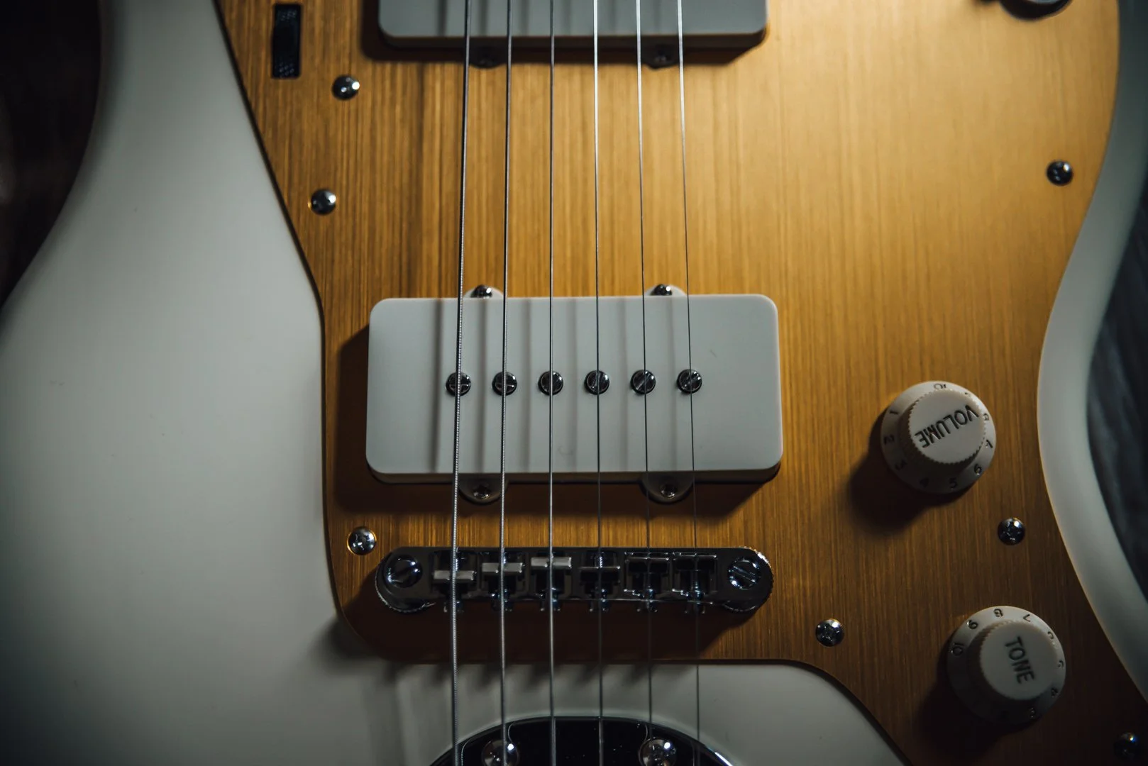 Close-up of an electric guitar's body, showing strings, pickups, and control knobs.