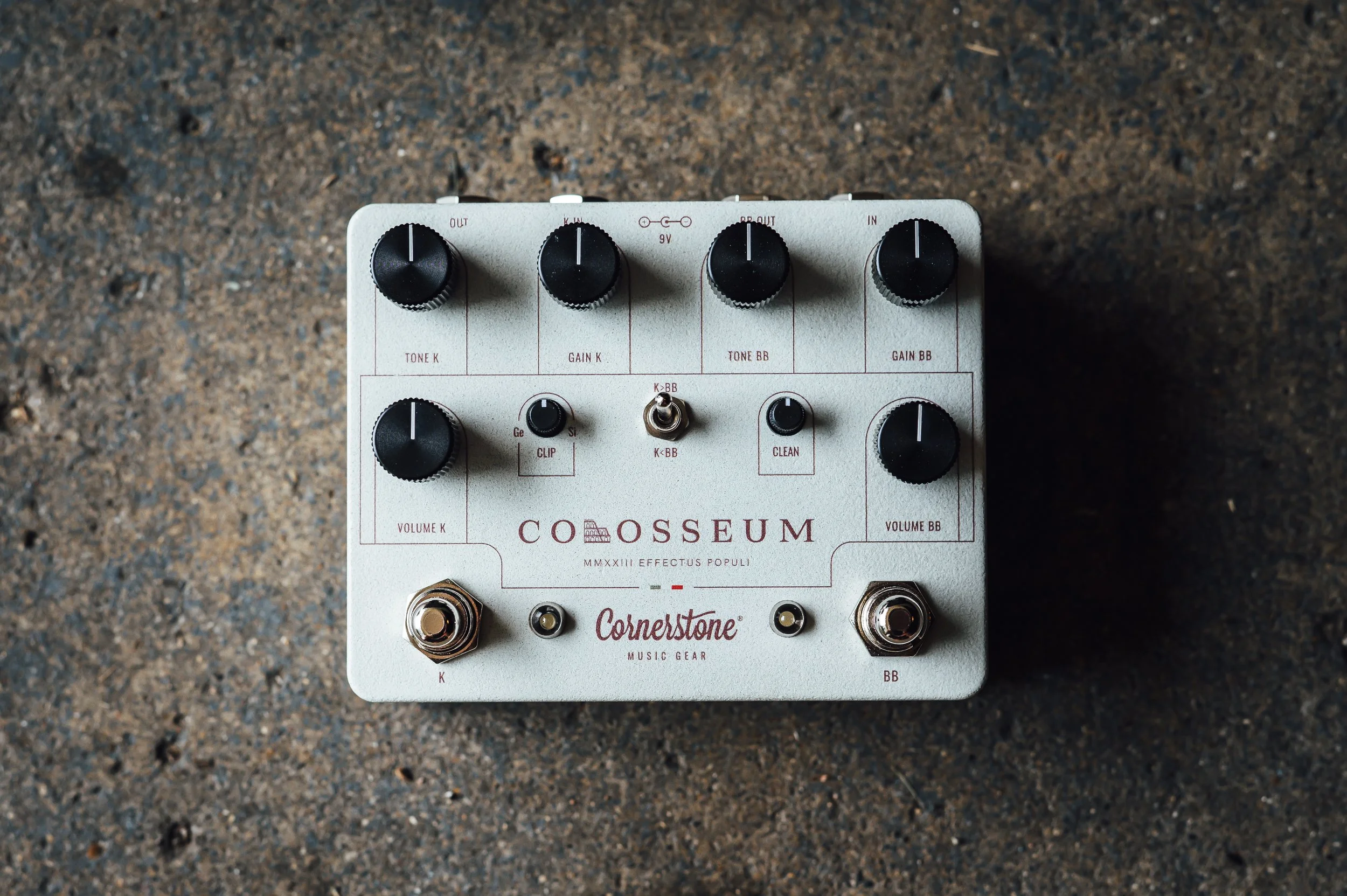 An effects pedal with multiple knobs and switches on a textured surface.