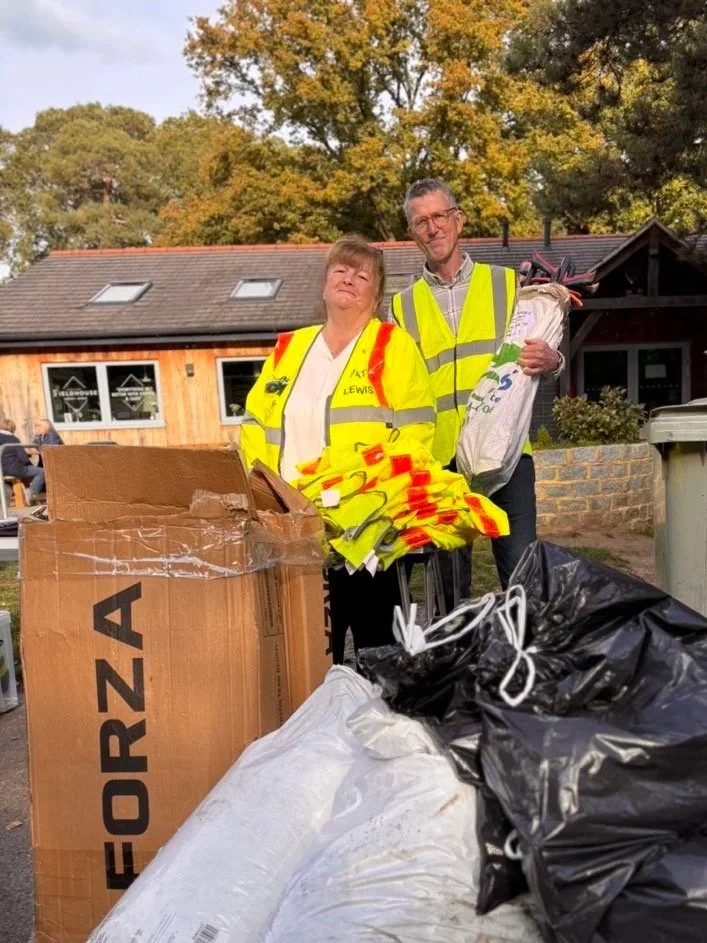 Two Windlesham Society Committee Members in high vis jackets outside the field of remembrance hub after a litter pick event