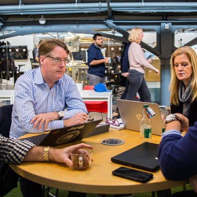 Team collaborating around a table in a modern workspace, representing the 2143 commercial capability framework in action.