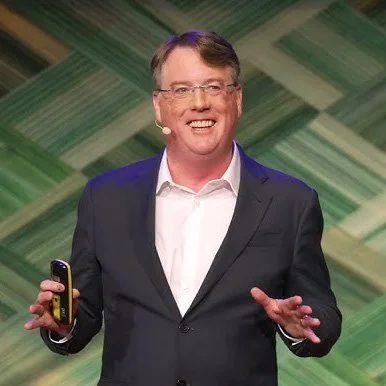 “Professional speaker delivering a keynote on agriculture and food systems, standing on stage against a green geometric backdrop.