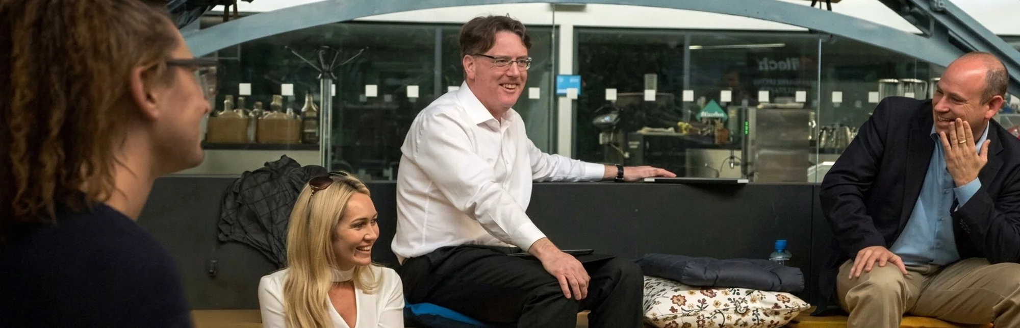“Aidan Connolly in conversation with leaders in a modern workspace, illustrating his coaching approach to building commercial momentum and driving decisive action.